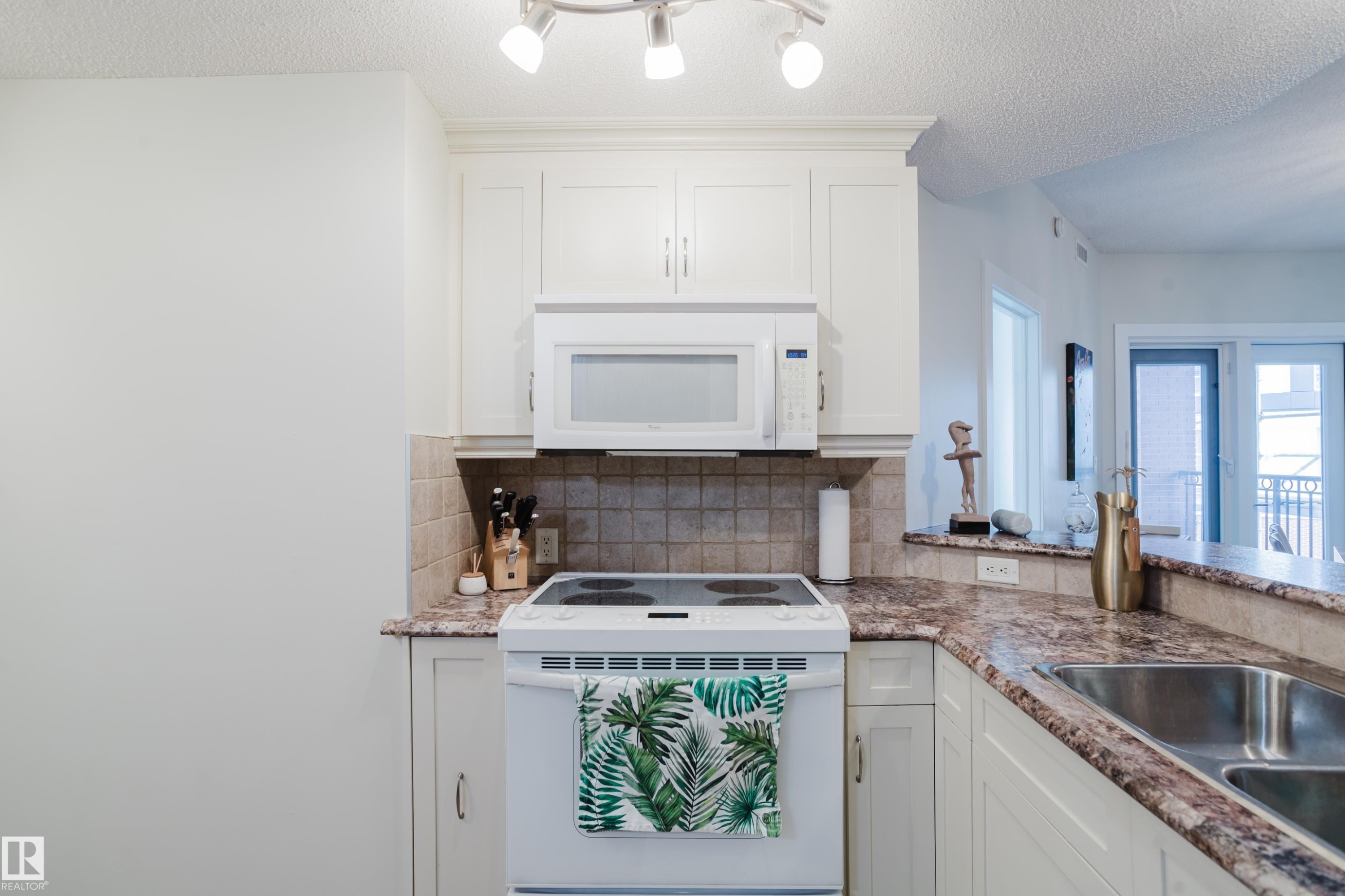 Kitchen featuring white cabinetry, a built-in microwave, an electric range, and a double basin sink - 206 10108 125 Street, Edmonton, AB - Indoor Photo Showing Kitchen With Double Sink