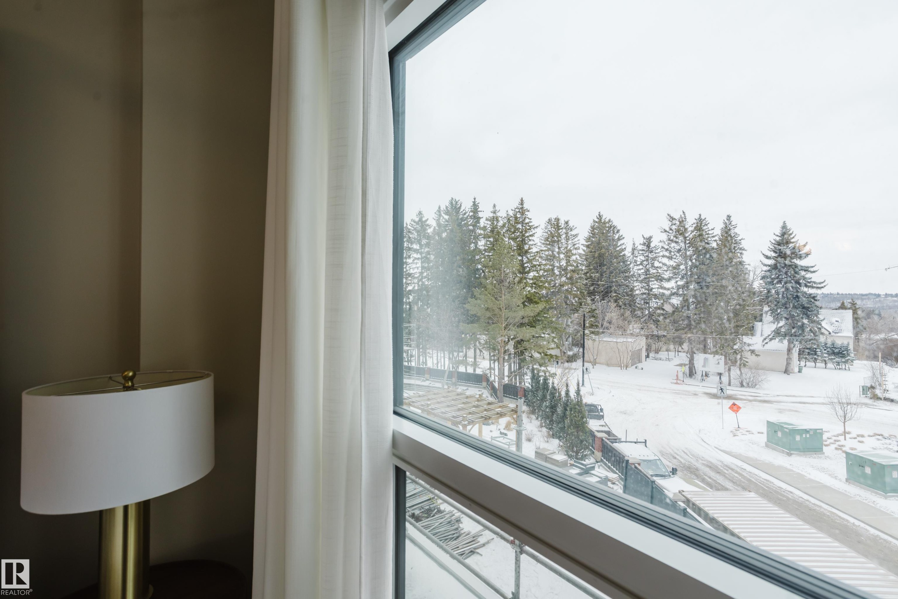 Expansive window offering views of the surrounding natural landscape, including mature trees and a snow-covered street - 206 10108 125 Street, Edmonton, AB - Indoor