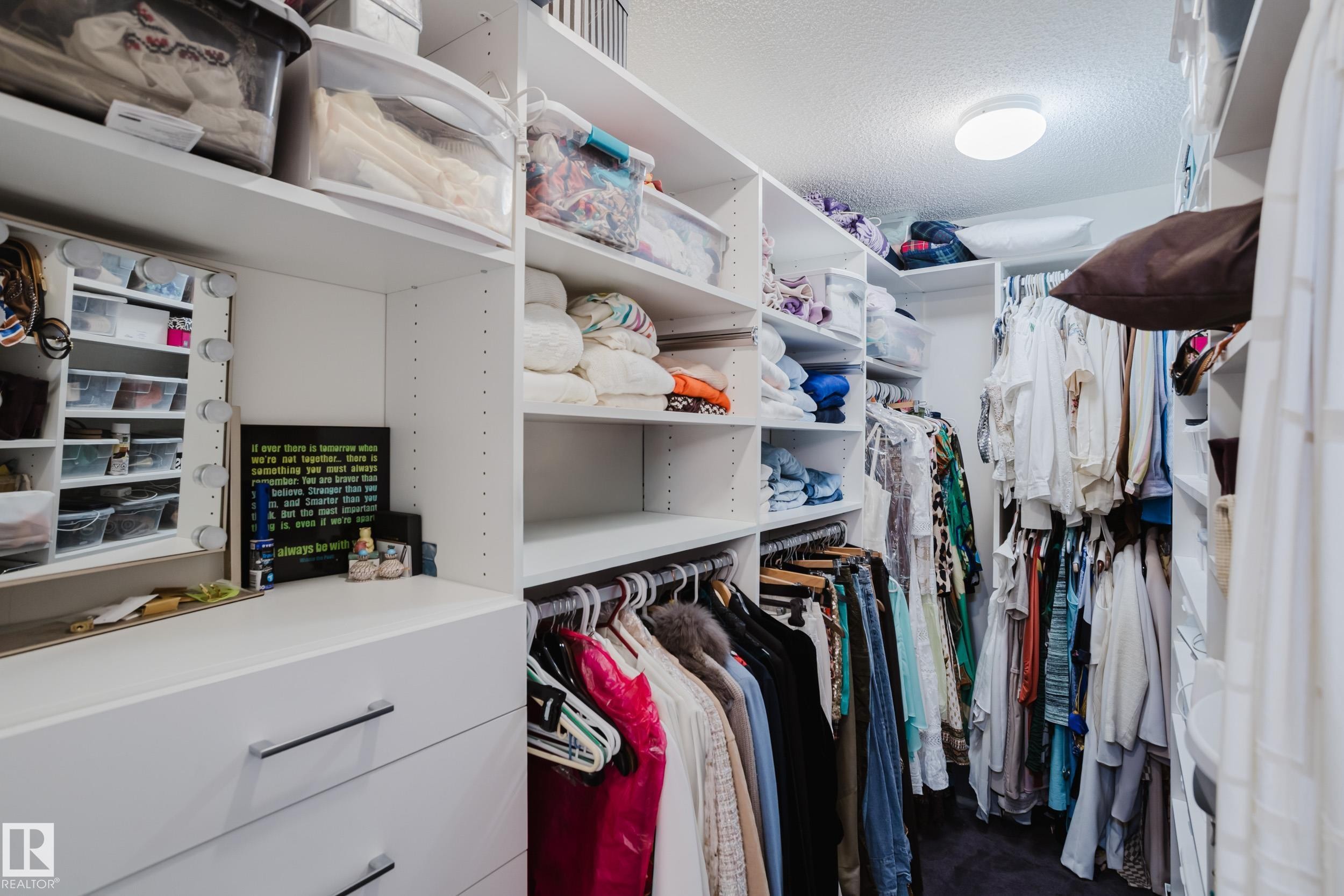The property includes a walk-in wardrobe featuring extensive white built-in shelving, integrated drawers with metal pull handles, and a ceiling-mounted light fixture - 206 10108 125 Street, Edmonton, AB - Indoor With Storage
