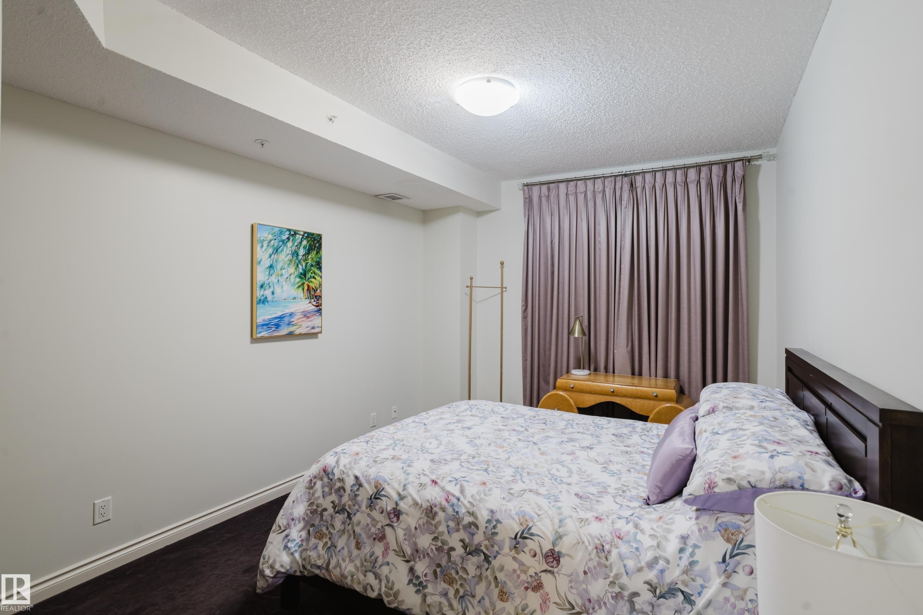 This bedroom features dark flooring, light-colored walls, and a ceiling light fixture - 206 10108 125 Street, Edmonton, AB - Indoor Photo Showing Bedroom
