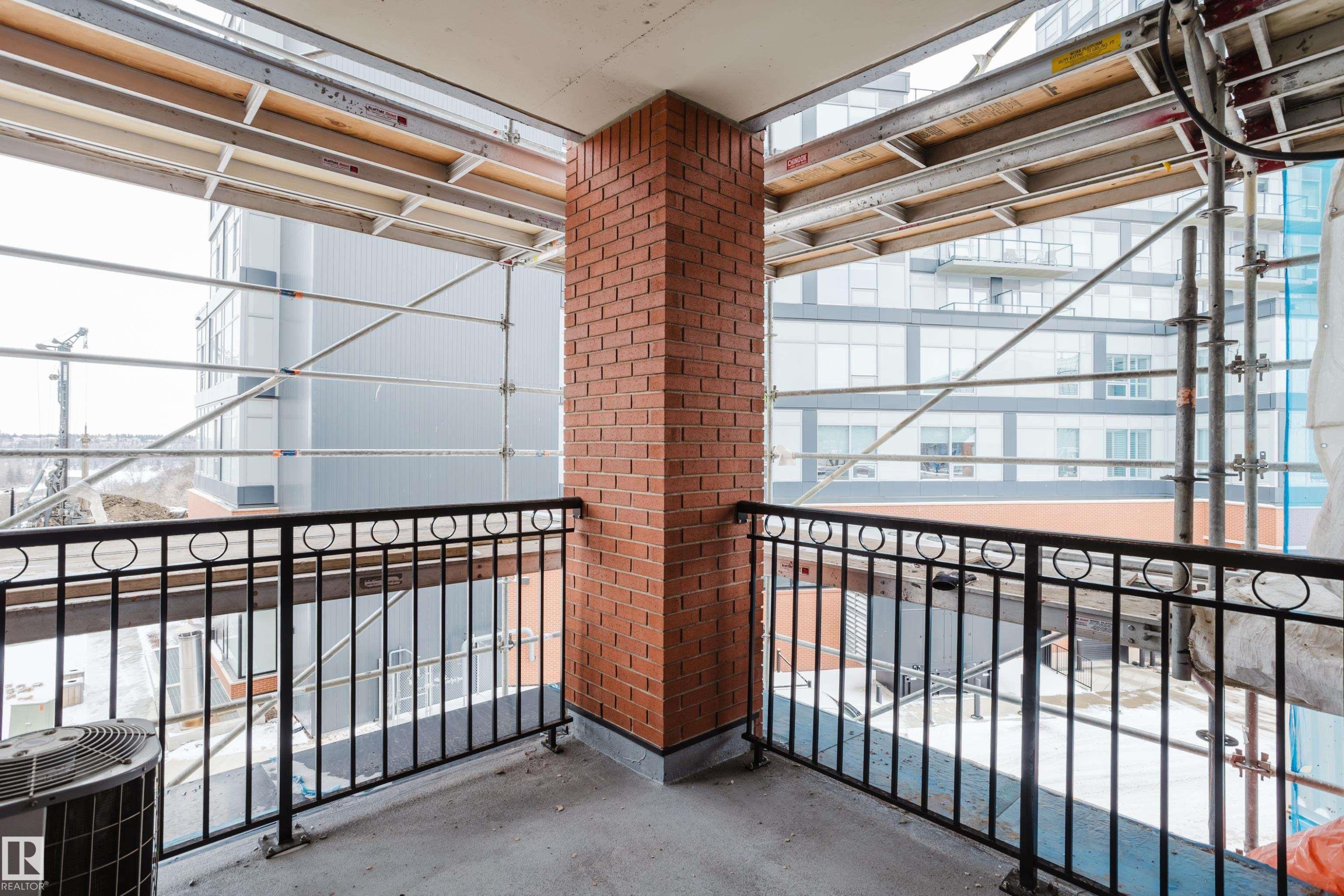 The property includes a private balcony with a brick wall and a black metal railing - 206 10108 125 Street, Edmonton, AB - Indoor Photo Showing Other Room