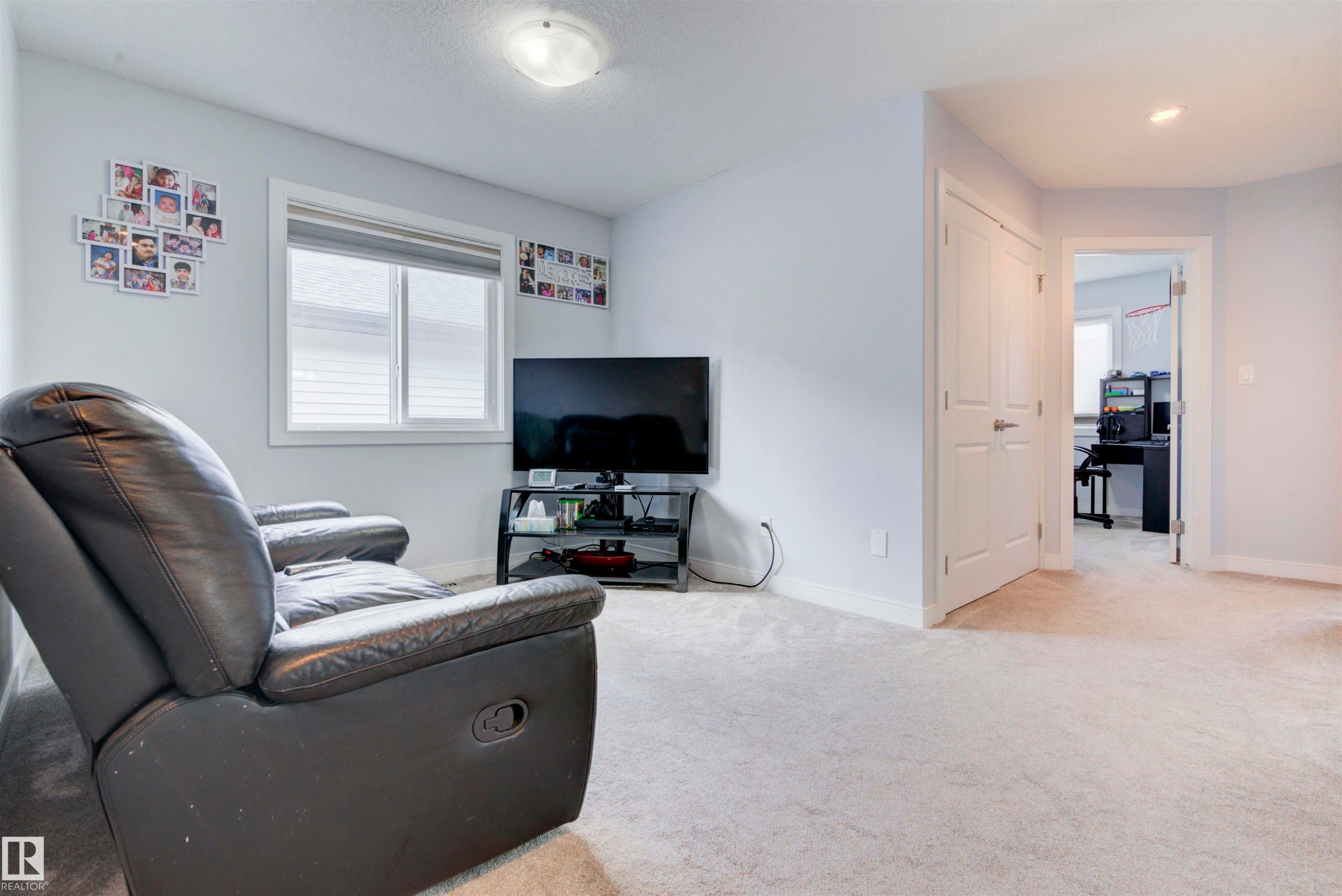This area features light-colored carpeting, a window with blinds for natural light, and a white door - 8452 Cushing Crest, Edmonton, AB - Indoor