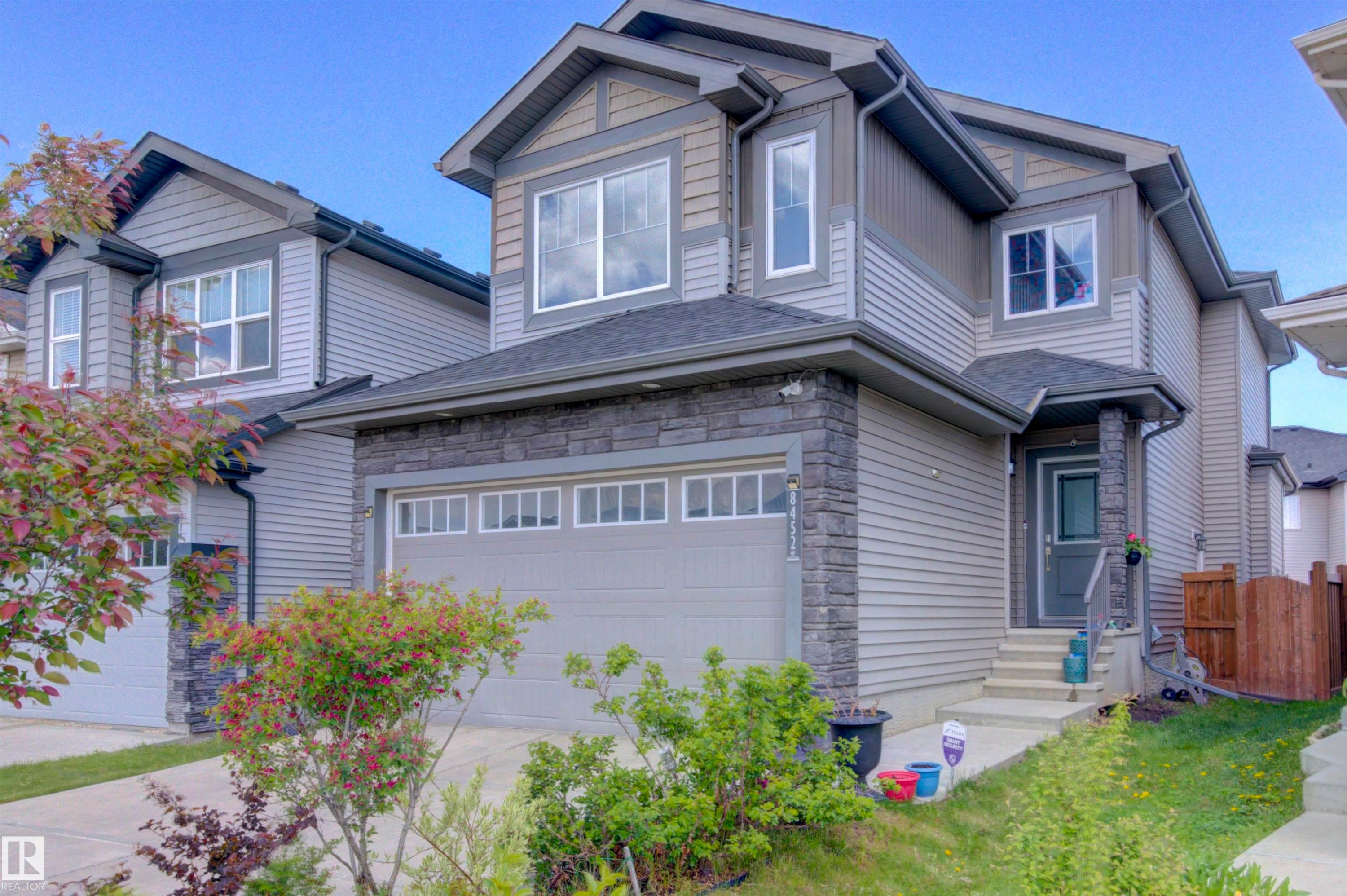 The property features a two-story exterior with light gray siding and dark grey stone accents - 8452 Cushing Crest, Edmonton, AB - Outdoor