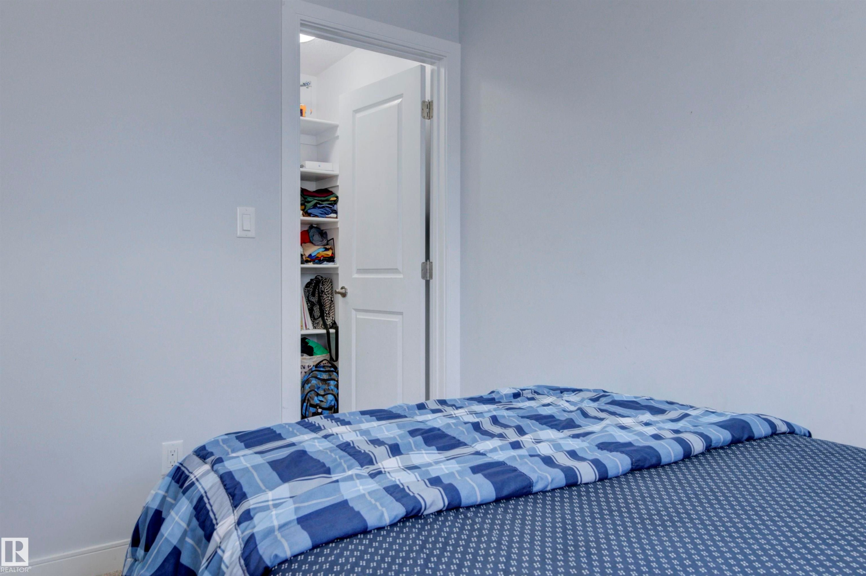 The property features a room with light-colored walls and a closet with shelving - 8452 Cushing Crest, Edmonton, AB - Indoor Photo Showing Bedroom
