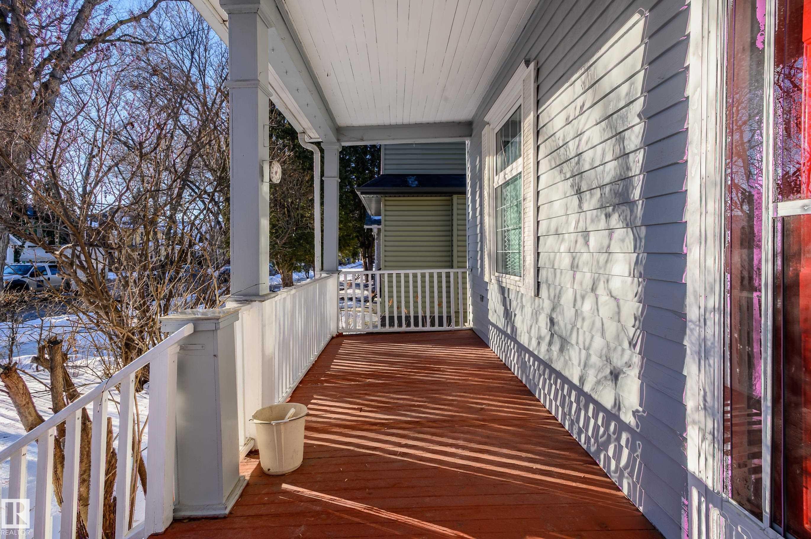 Covered front porch featuring a wood-finish floor, white railing, and paneled ceiling - 10918 81 Avenue, Edmonton, AB - Outdoor With Exterior