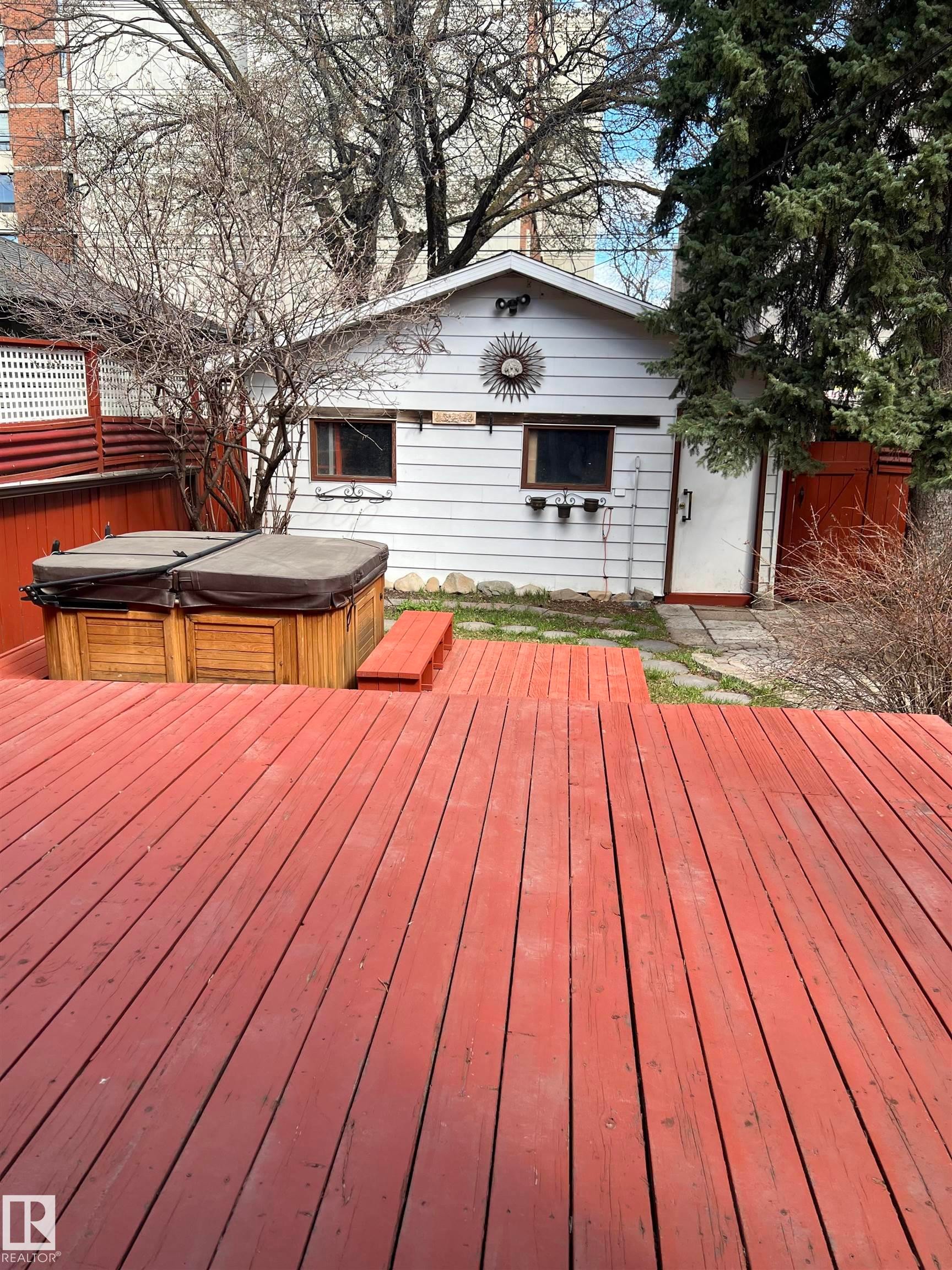 Expansive red-stained wooden deck featuring a built-in hot tub - 10918 81 Avenue, Edmonton, AB - Outdoor