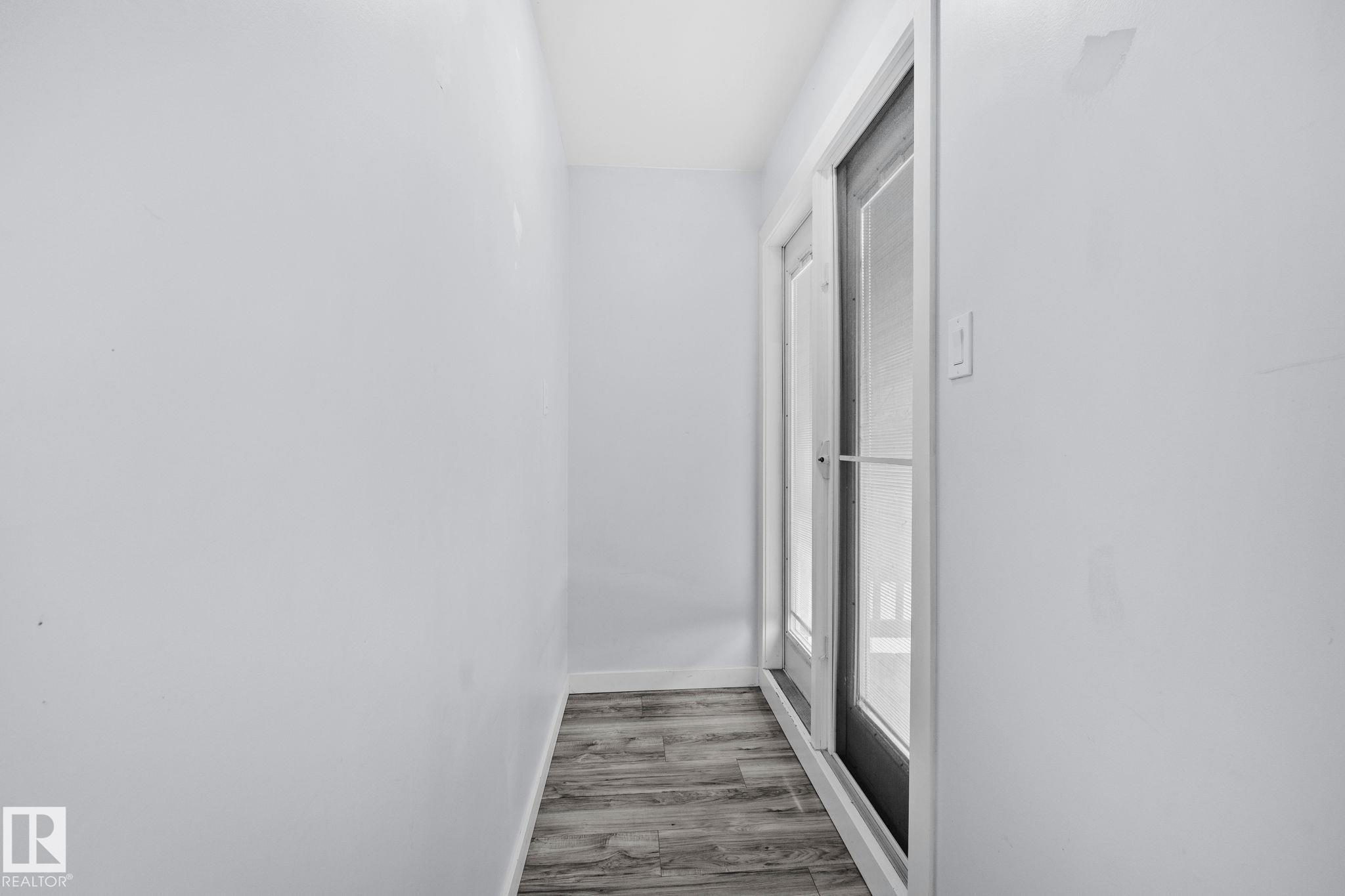 Hallway featuring light-colored walls, wood-look flooring, and a glass-paneled door - 12002 37 Street, Edmonton, AB - Indoor Photo Showing Other Room
