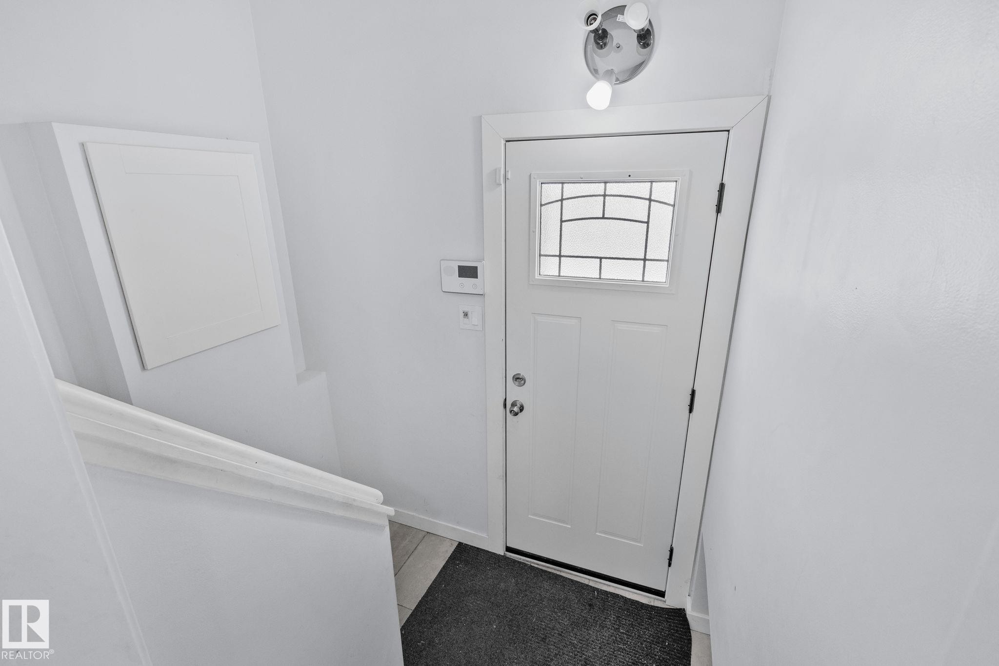 Entryway featuring a white door with a decorative glass insert, a ceiling-mounted light fixture, and a dark floor mat - 12002 37 Street, Edmonton, AB - Indoor Photo Showing Other Room