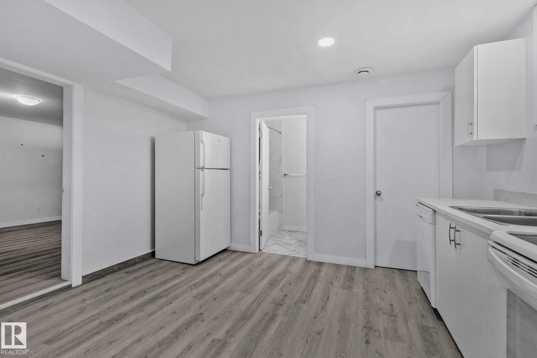 The kitchen features white cabinetry, a double basin sink, and a refrigerator - 12002 37 Street, Edmonton, AB - Indoor Photo Showing Kitchen With Double Sink