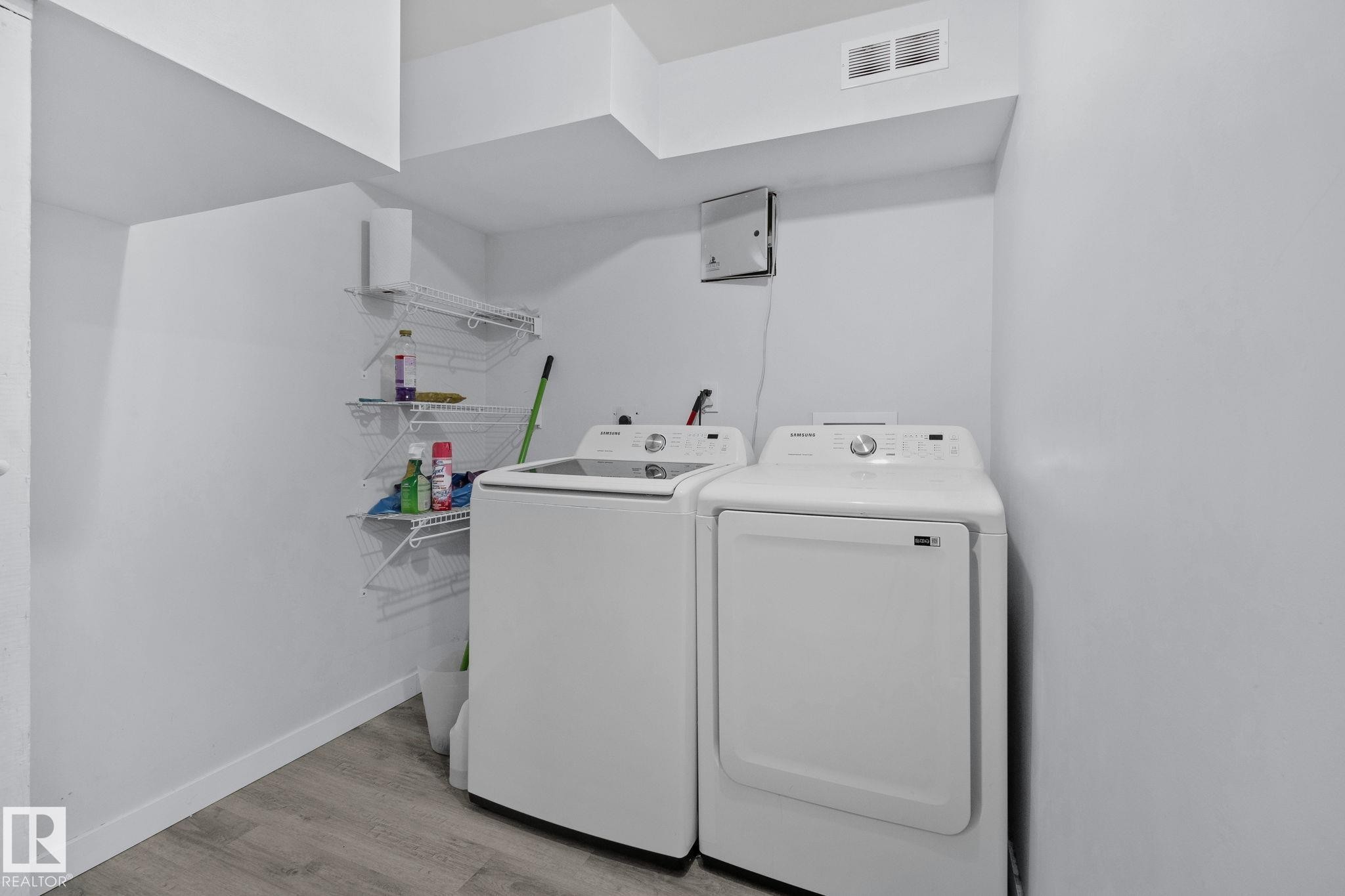 Laundry area with a washer and dryer, white wire shelving, and light wood-style flooring - 12002 37 Street, Edmonton, AB - Indoor Photo Showing Laundry Room