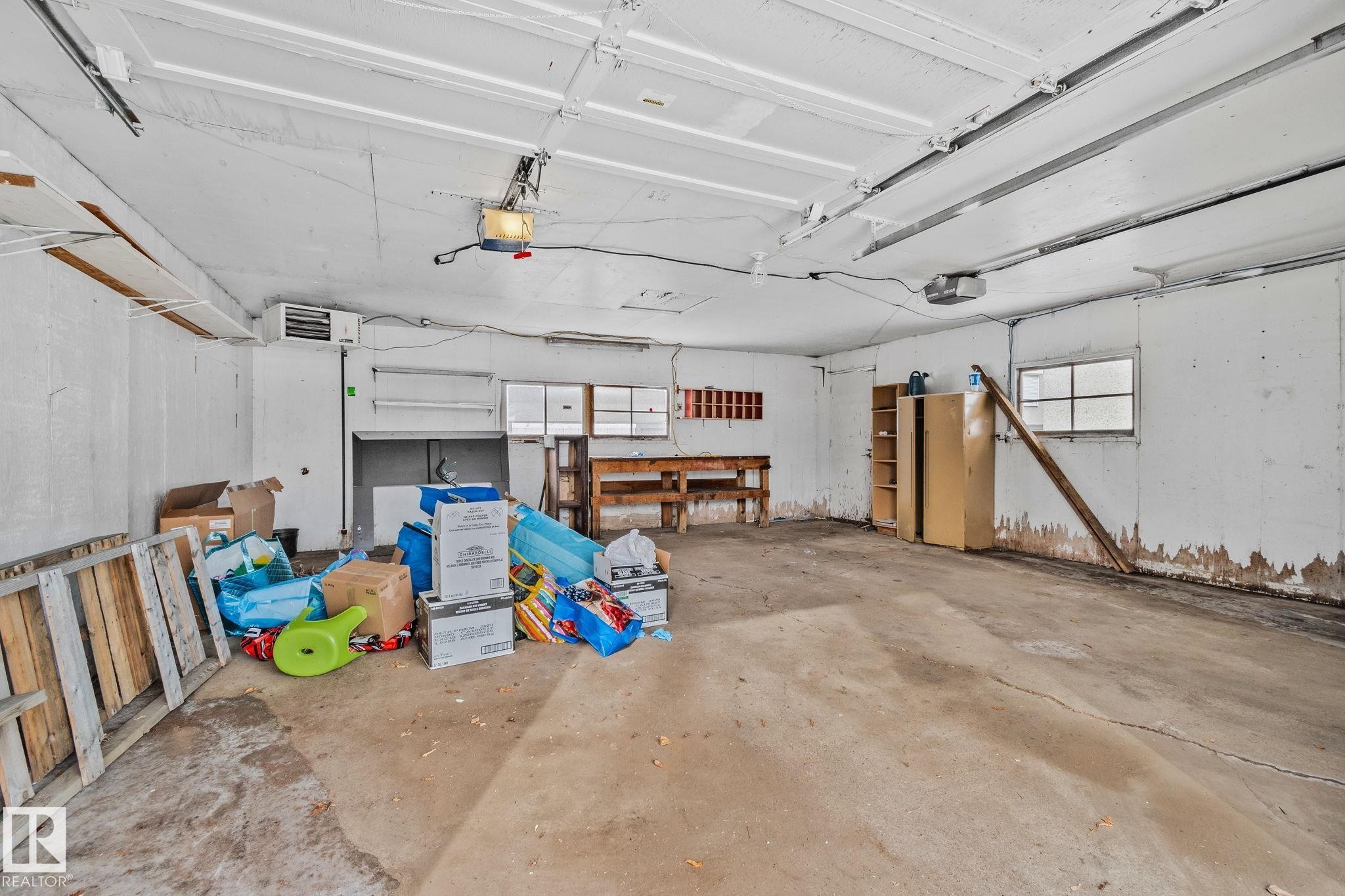 The property features a spacious garage with a concrete floor, multiple windows, and a built-in workbench - 12002 37 Street, Edmonton, AB - Indoor Photo Showing Garage