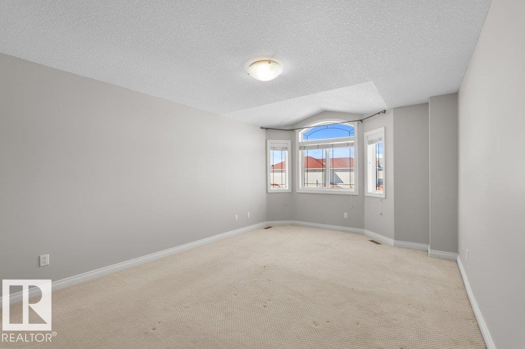 This room features a neutral color palette, a large bay window, and light-colored carpeting - 16419 53 Street, Edmonton, AB - Indoor Photo Showing Other Room