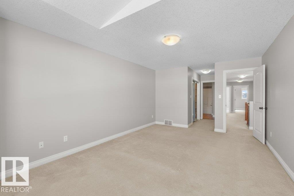 This interior space features light grey walls and beige carpet - 16419 53 Street, Edmonton, AB - Indoor Photo Showing Other Room