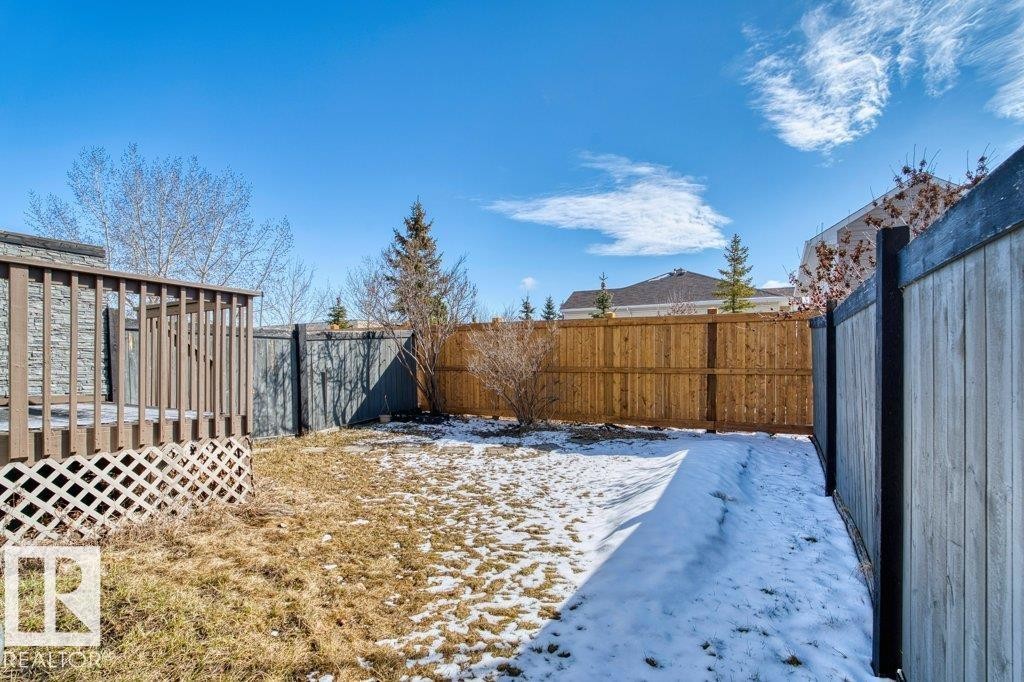 The property features an outdoor deck with lattice skirting, a fenced yard with a mix of wood and stained fences, and a lawn area - 16419 53 Street, Edmonton, AB - Outdoor
