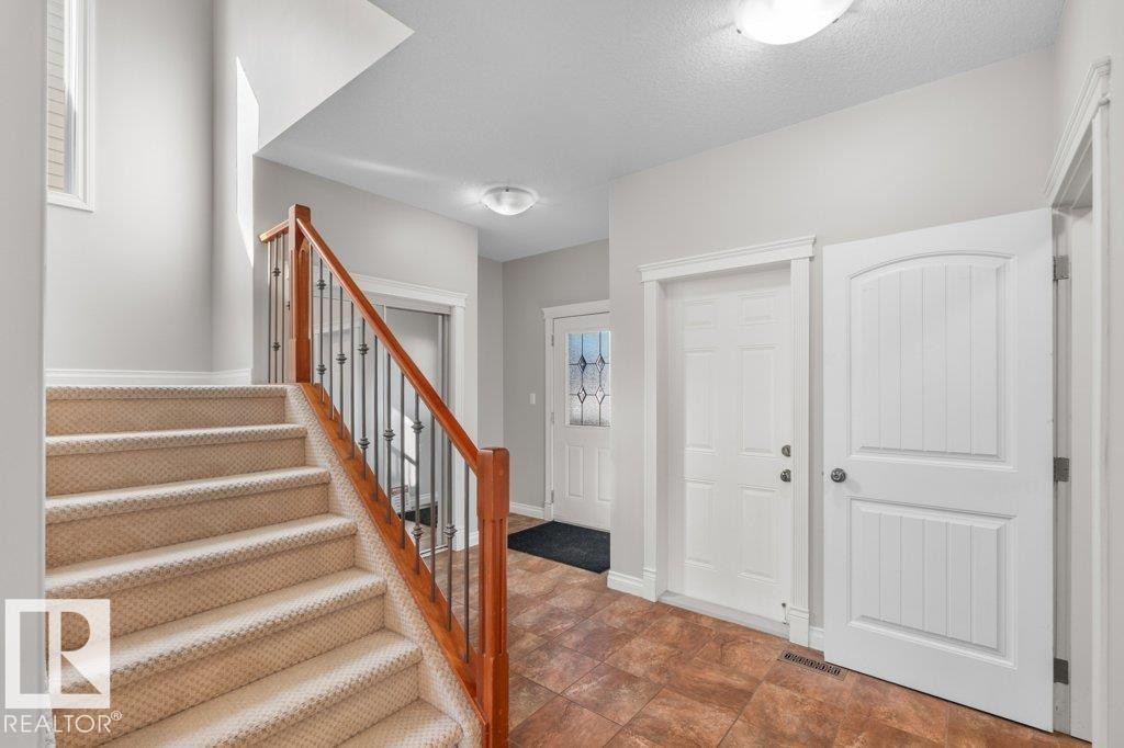 Inviting entryway featuring tiled flooring, white doors, and a carpeted staircase with a wooden handrail and decorative metal balusters - 16419 53 Street, Edmonton, AB - Indoor Photo Showing Other Room