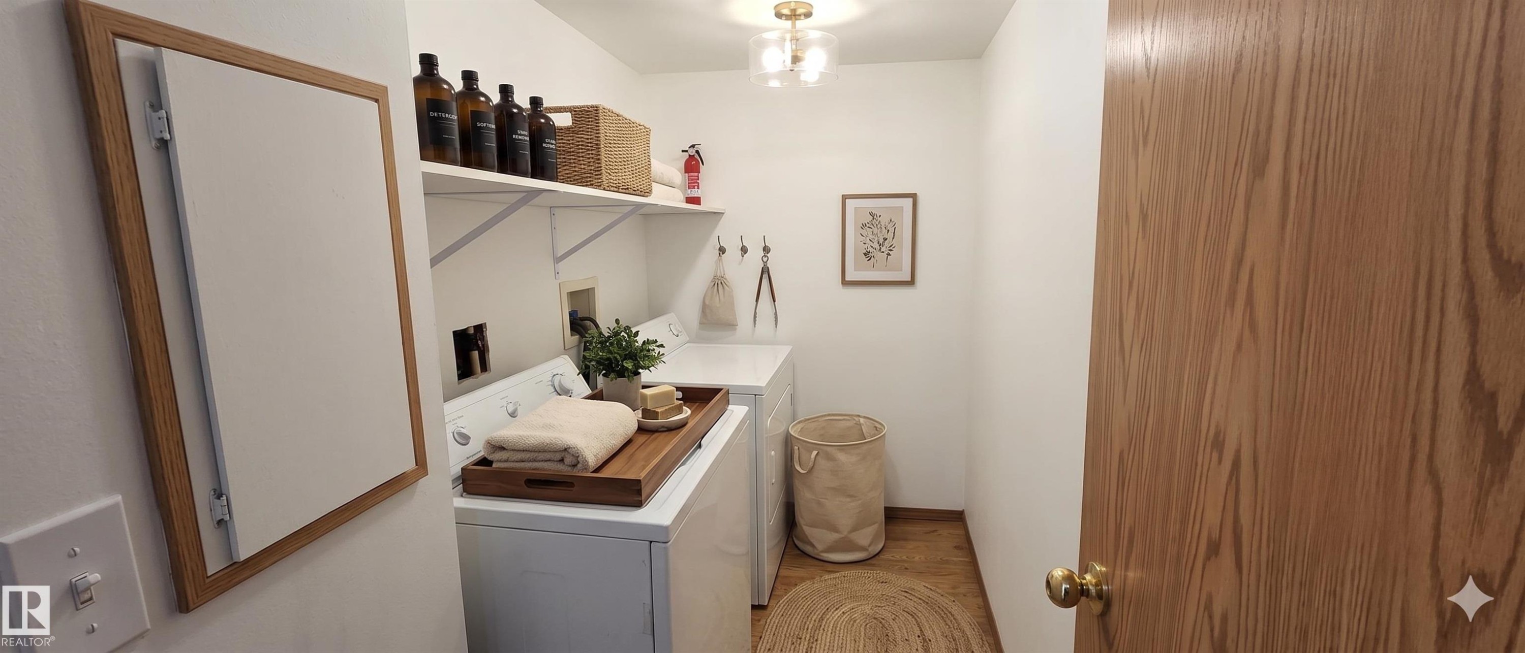 Dedicated laundry area featuring a white washer and dryer, open shelving, and wood-look flooring - 208A 260 Spruce Ridge Road, Spruce Grove, AB - Indoor