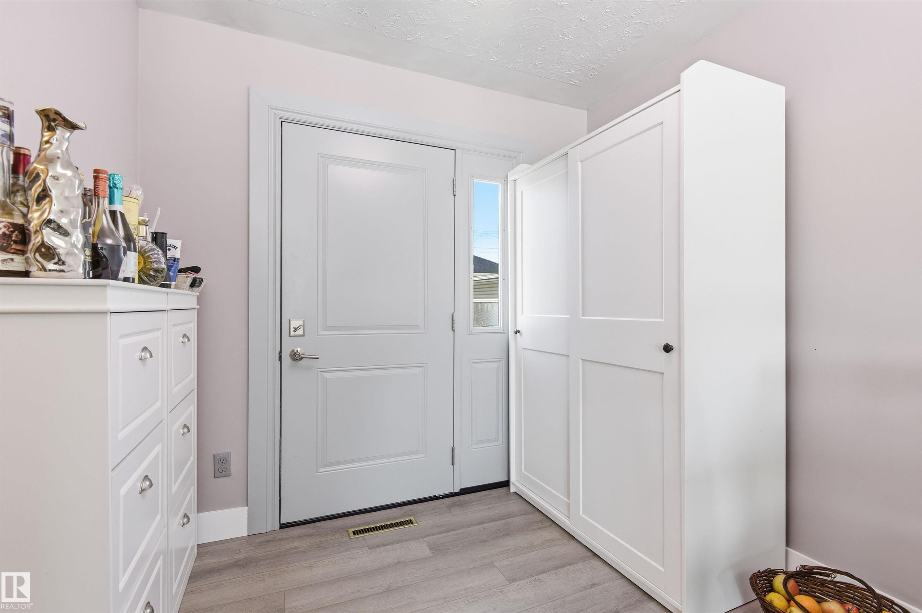 Entryway featuring light-toned flooring, a white door with a clear glass sidelight, and built-in white storage cabinetry - 12904 95 Street, Edmonton, AB - Indoor Photo Showing Other Room