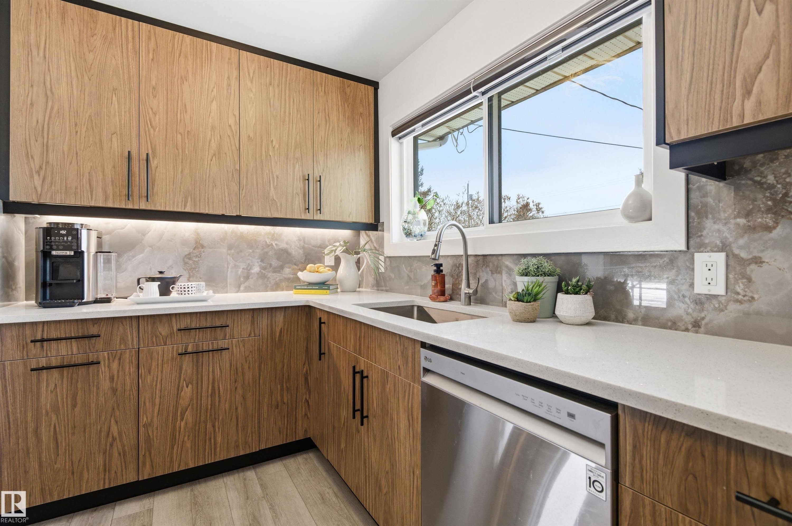 The kitchen features wood cabinetry, light countertops, and a stainless steel dishwasher - 12904 95 Street, Edmonton, AB - Indoor Photo Showing Kitchen