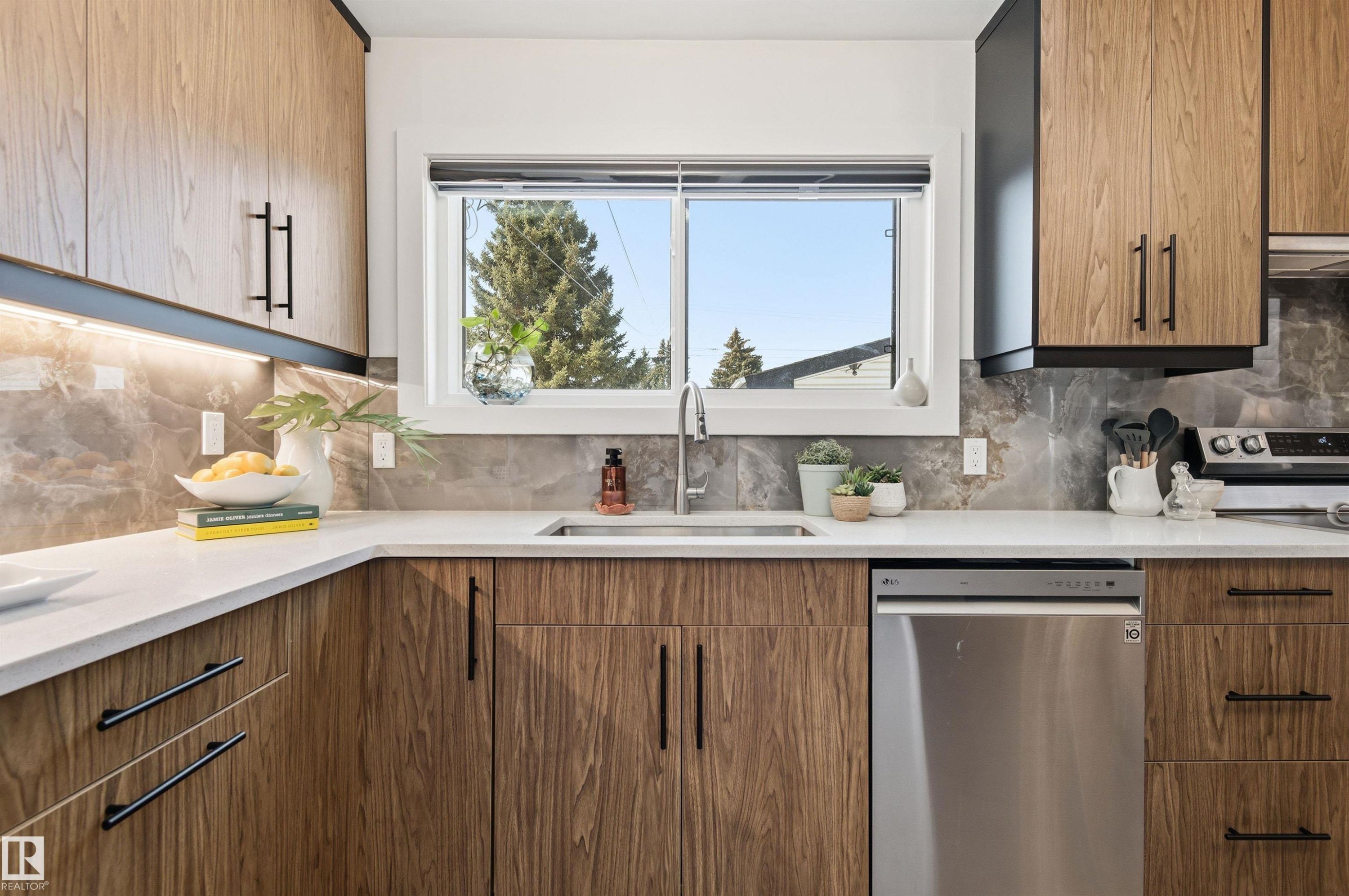 The kitchen features wood cabinetry, a white countertop, a stainless steel sink with a chrome faucet, and a stainless steel dishwasher - 12904 95 Street, Edmonton, AB - Indoor Photo Showing Kitchen With Upgraded Kitchen