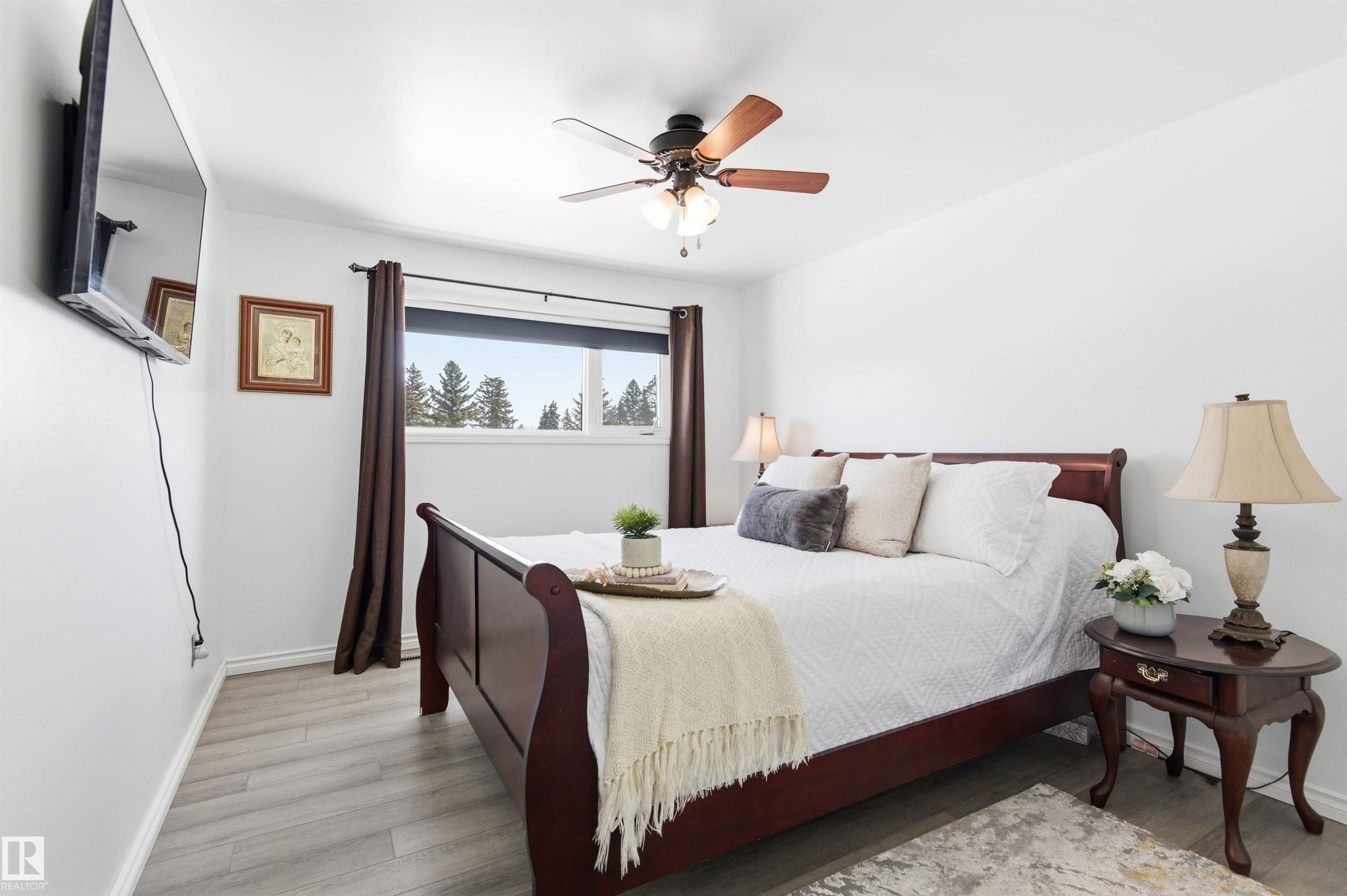 The room features light-colored flooring, a window with dark curtains, and a ceiling fan - 12904 95 Street, Edmonton, AB - Indoor Photo Showing Bedroom
