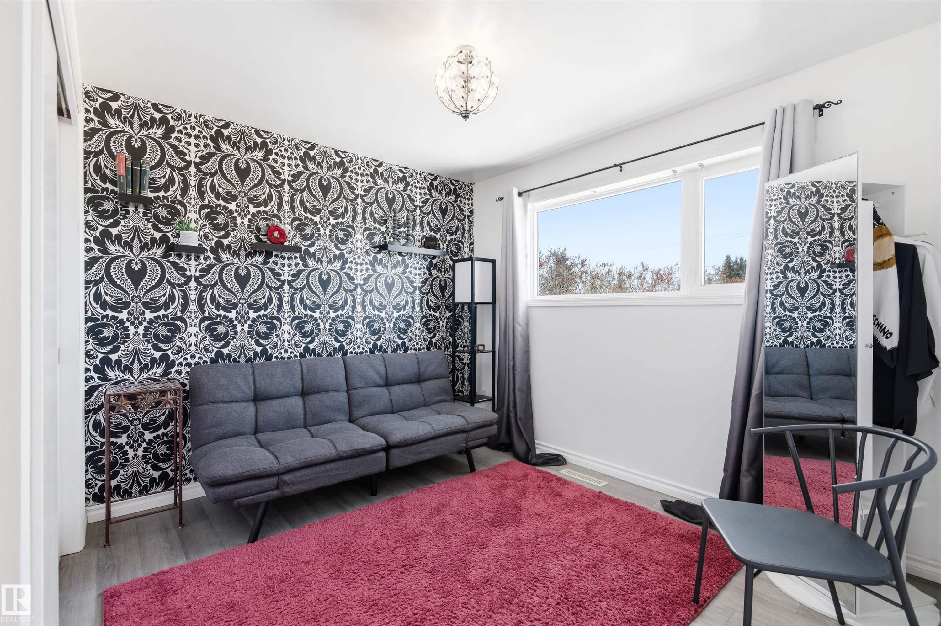 This room features a distinct accent wall with black and white patterned wallpaper, complemented by light grey flooring and a bright window - 12904 95 Street, Edmonton, AB - Indoor