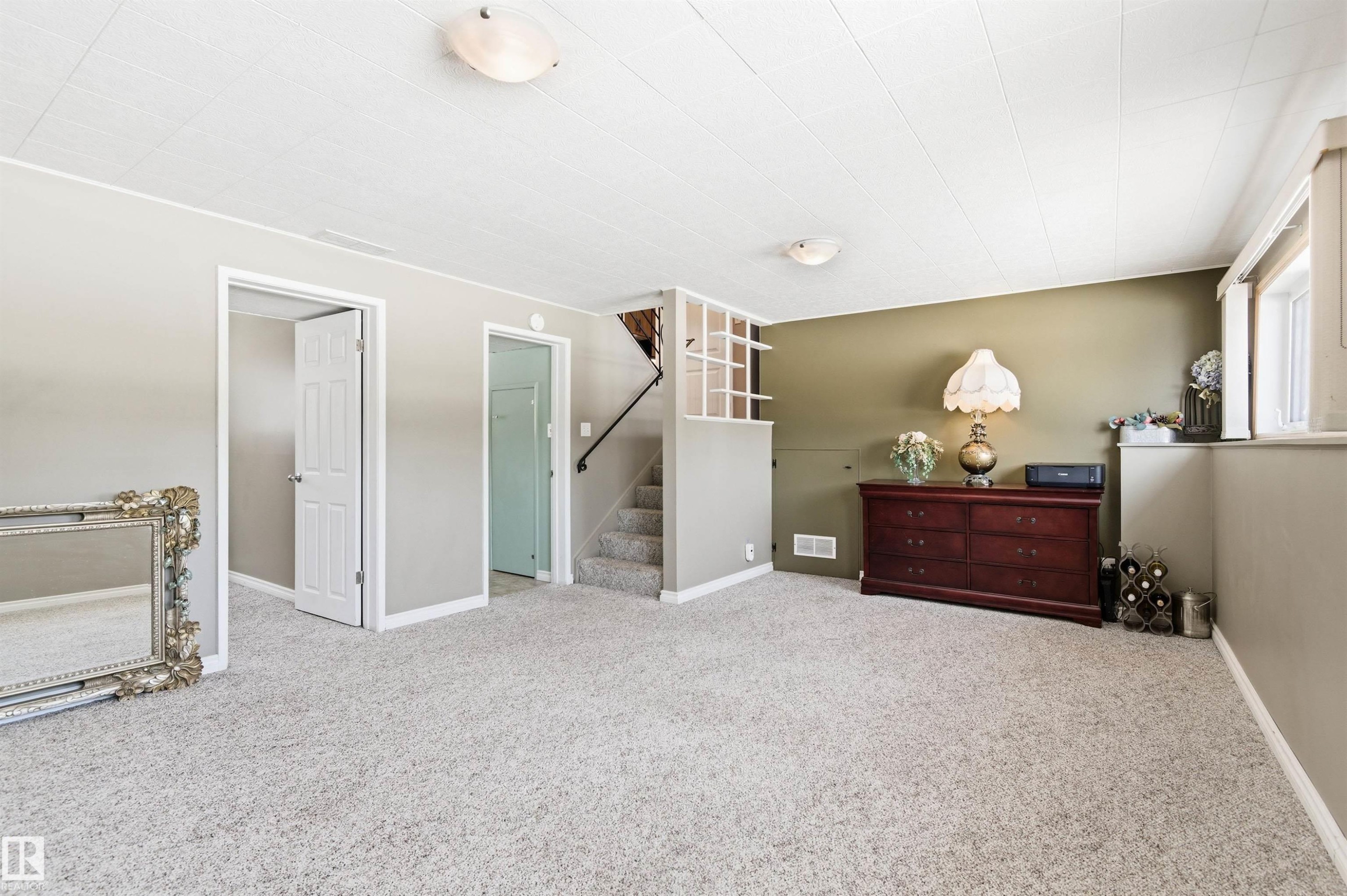 Spacious room featuring light-colored carpet, a window, and a staircase - 12904 95 Street, Edmonton, AB - Indoor Photo Showing Bedroom