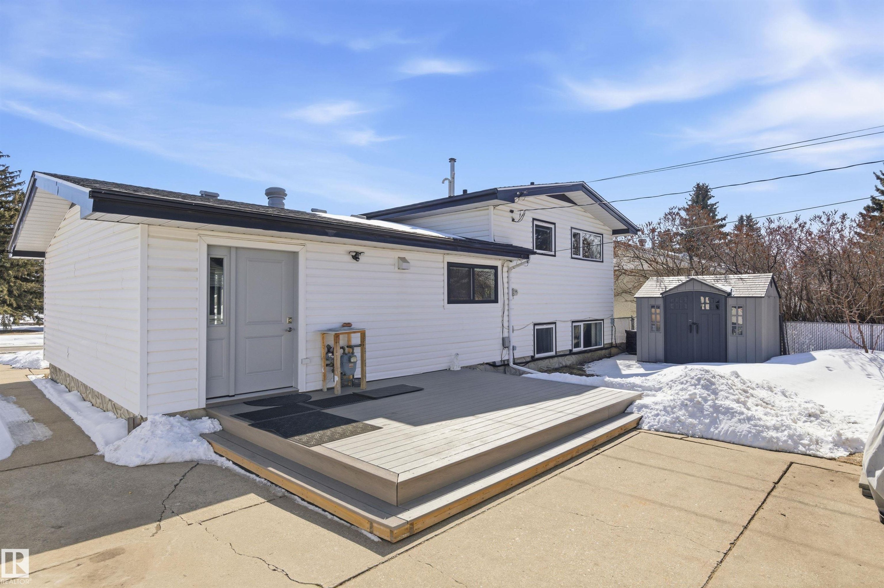 The property features a white exterior with black trim, a spacious deck, and a shed in the yard - 12904 95 Street, Edmonton, AB - Outdoor With Exterior