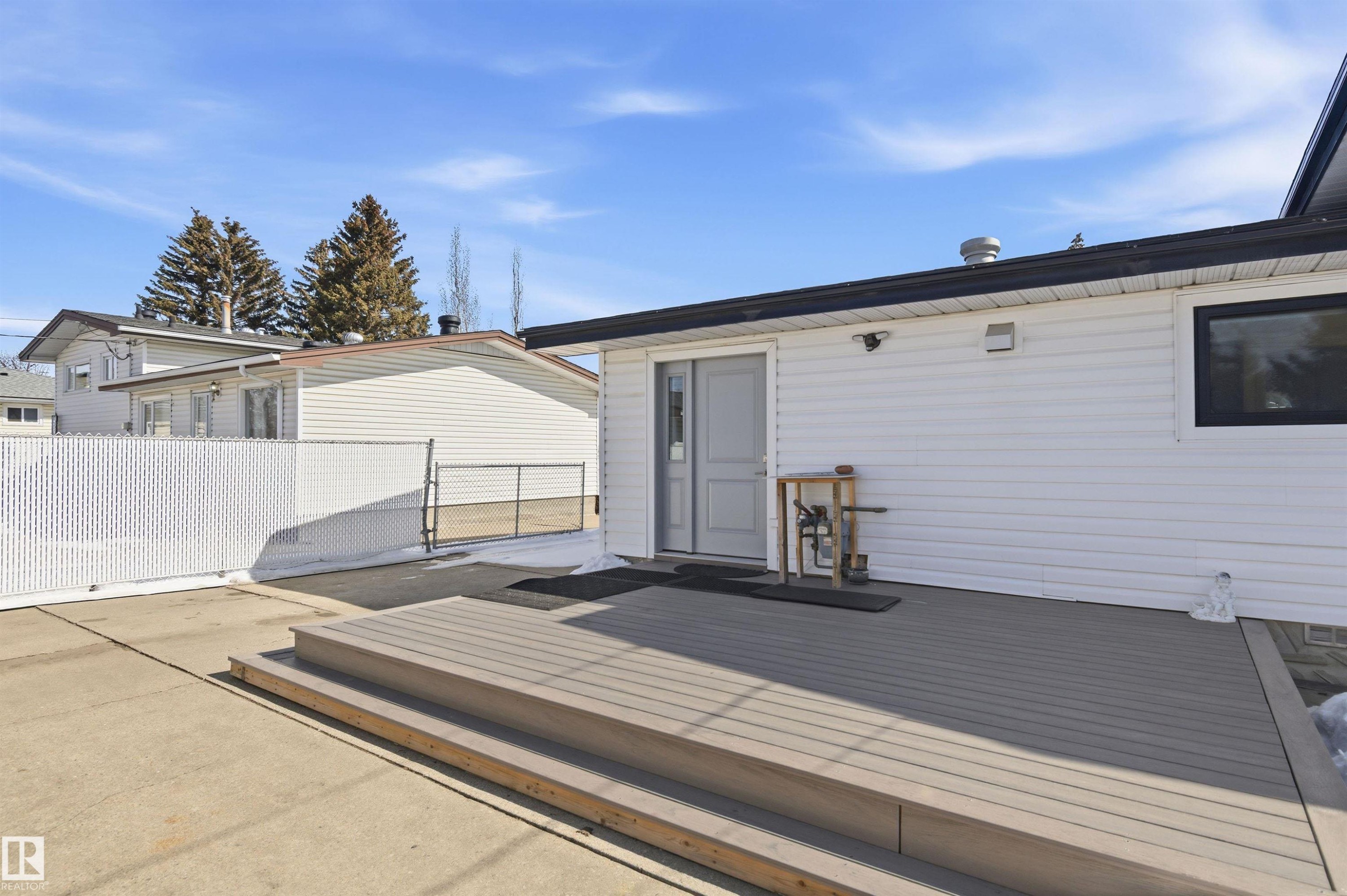 The property features a spacious rear deck with steps, a sliding glass door entry, and white vinyl siding - 12904 95 Street, Edmonton, AB - Outdoor With Exterior