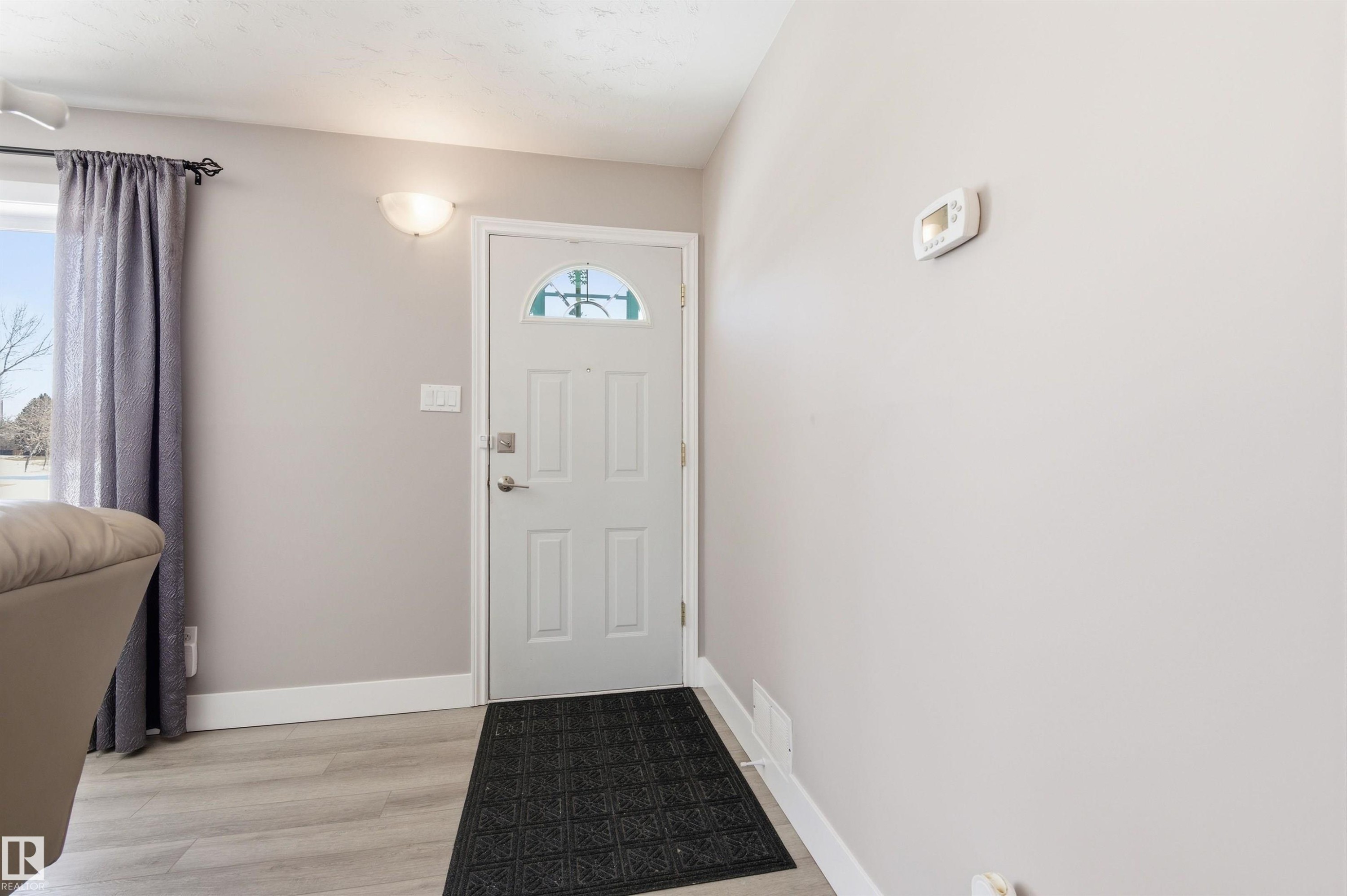 The entry features a front door with a decorative glass insert, light gray walls, and light-colored flooring - 12904 95 Street, Edmonton, AB - Indoor Photo Showing Other Room
