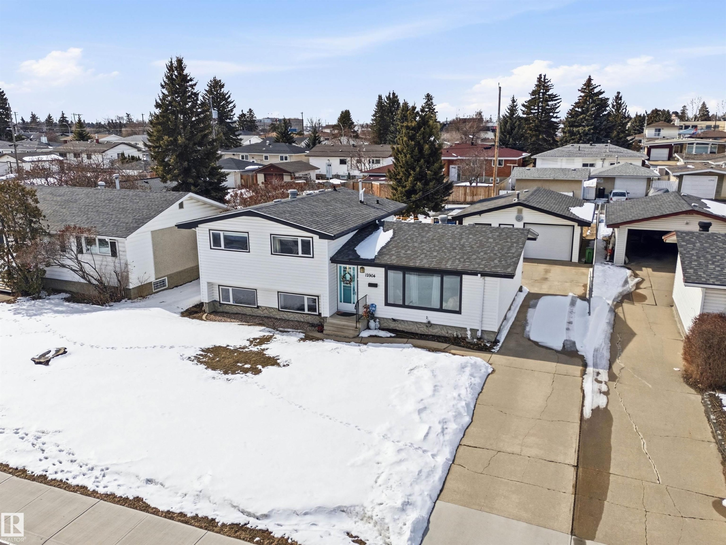 The property features a white exterior with a dark roof and a paved driveway - 12904 95 Street, Edmonton, AB - Outdoor