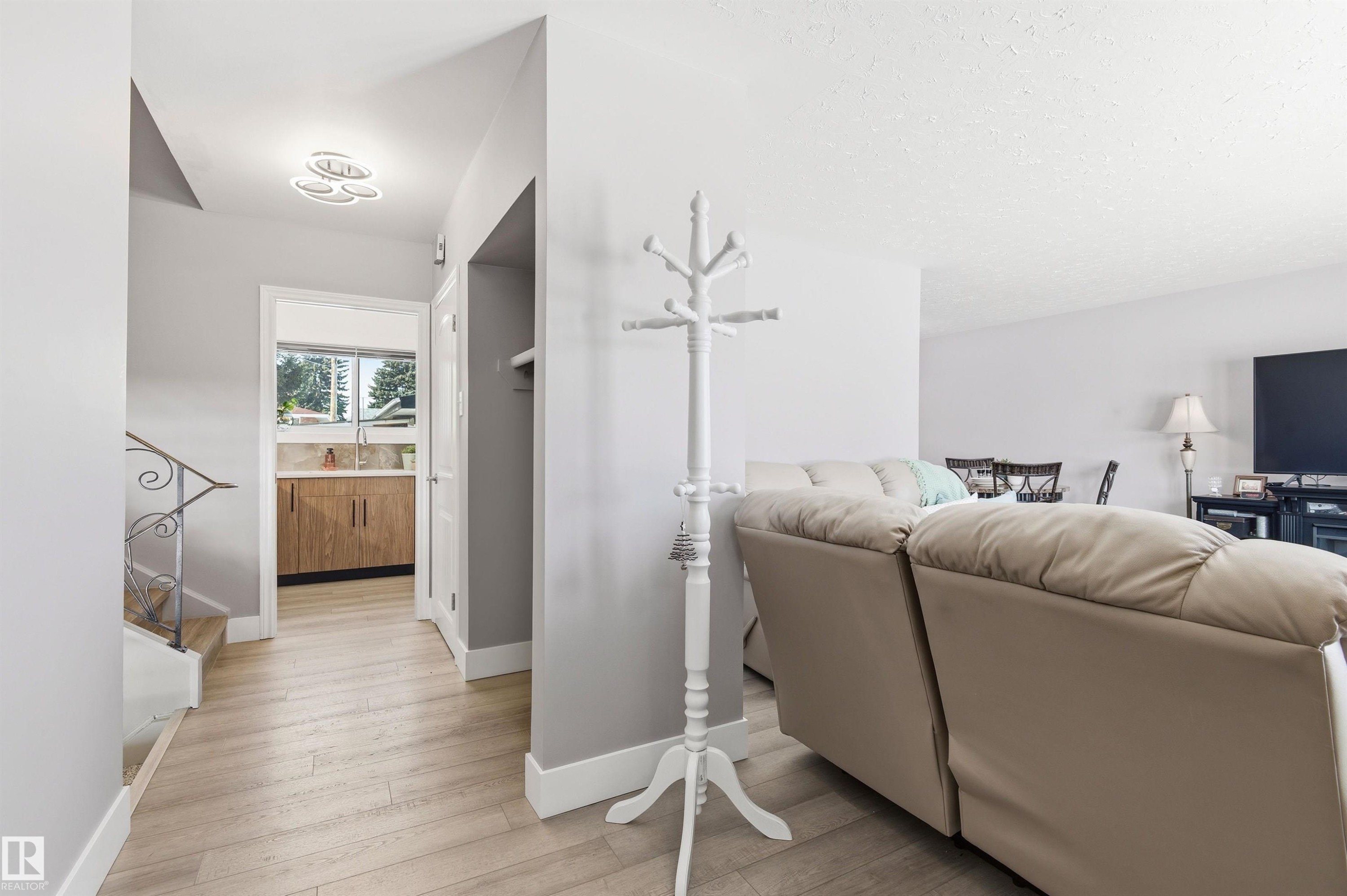 The property features light-colored flooring throughout the main entry area and into the adjacent room, which includes wood-toned cabinetry and a window - 12904 95 Street, Edmonton, AB - Indoor