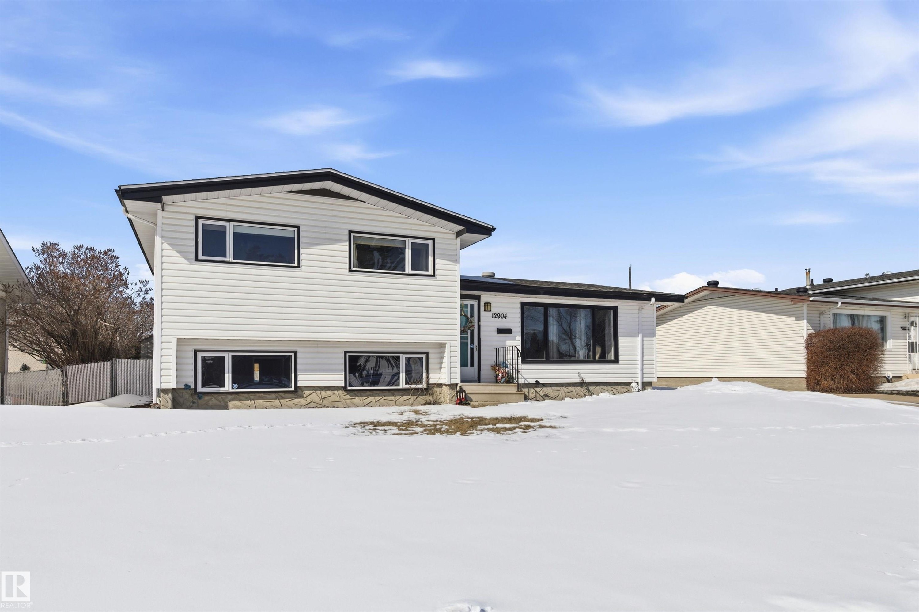 The property features white siding with black trim, a gabled roof, and a stone-clad foundation - 12904 95 Street, Edmonton, AB - Outdoor