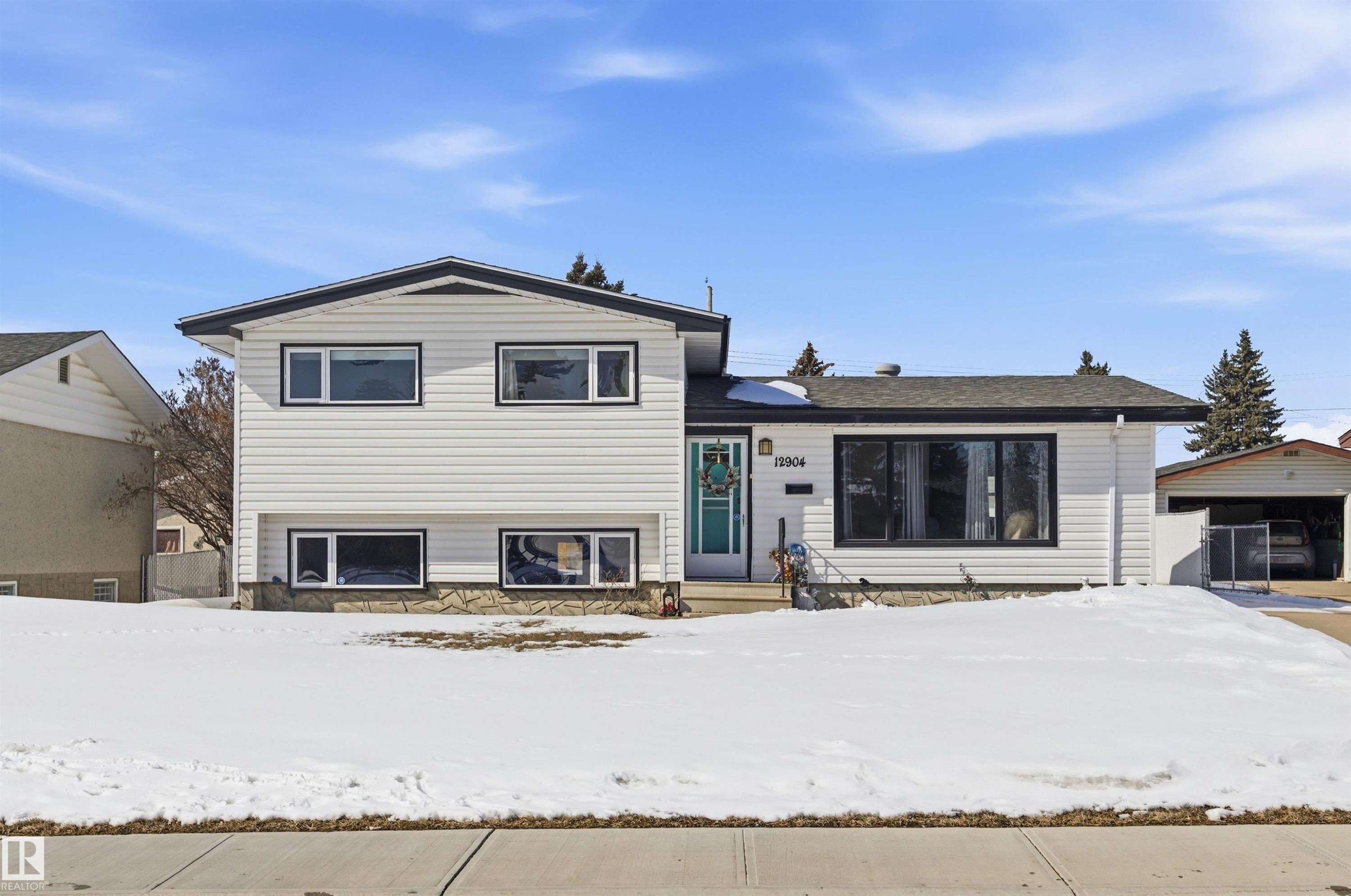 This property features white horizontal siding, dark window trim, and a turquoise front door - 12904 95 Street, Edmonton, AB - Outdoor With Facade