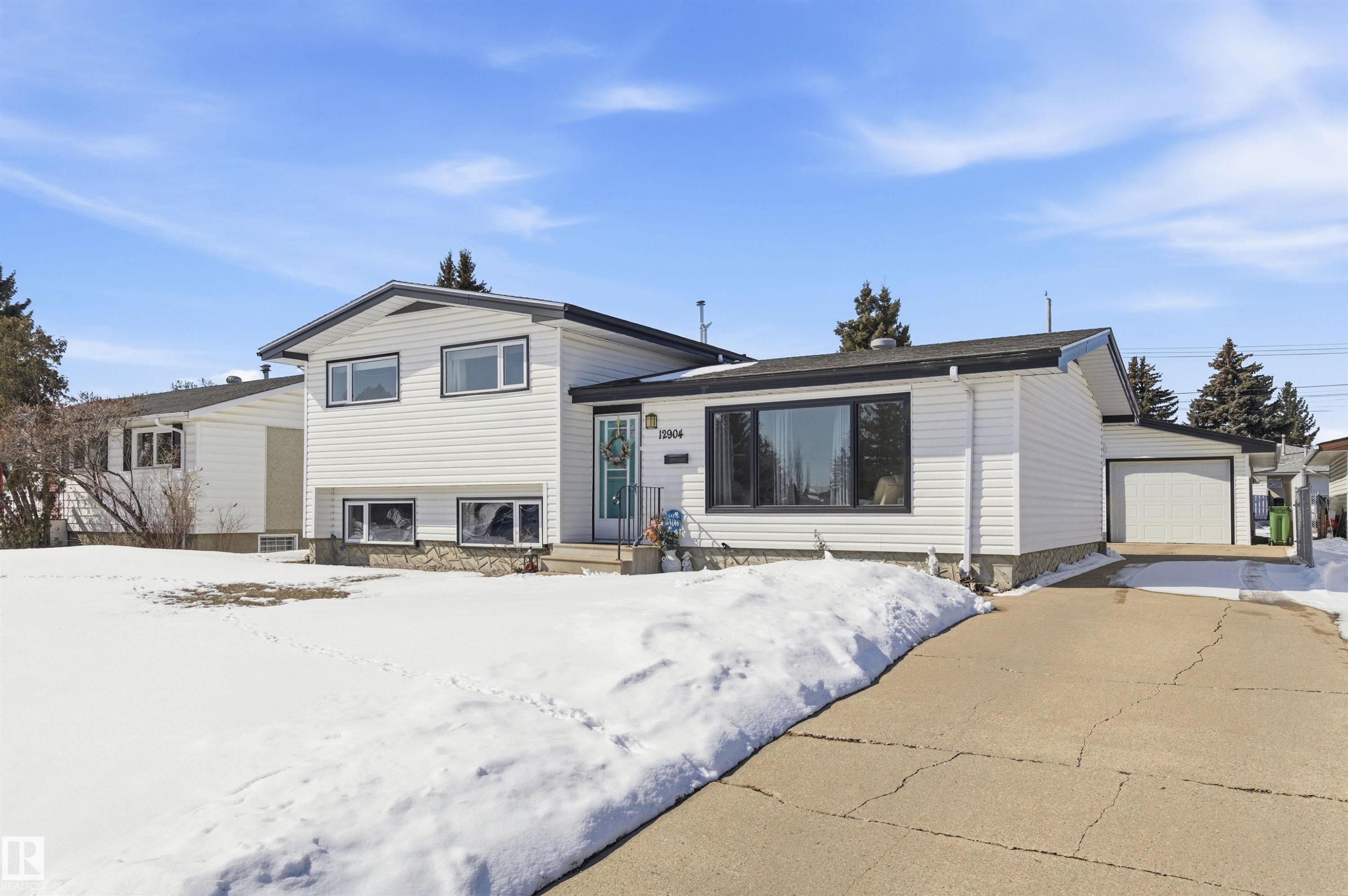 The property features white siding and dark trim, with a front yard and an attached garage - 12904 95 Street, Edmonton, AB - Outdoor
