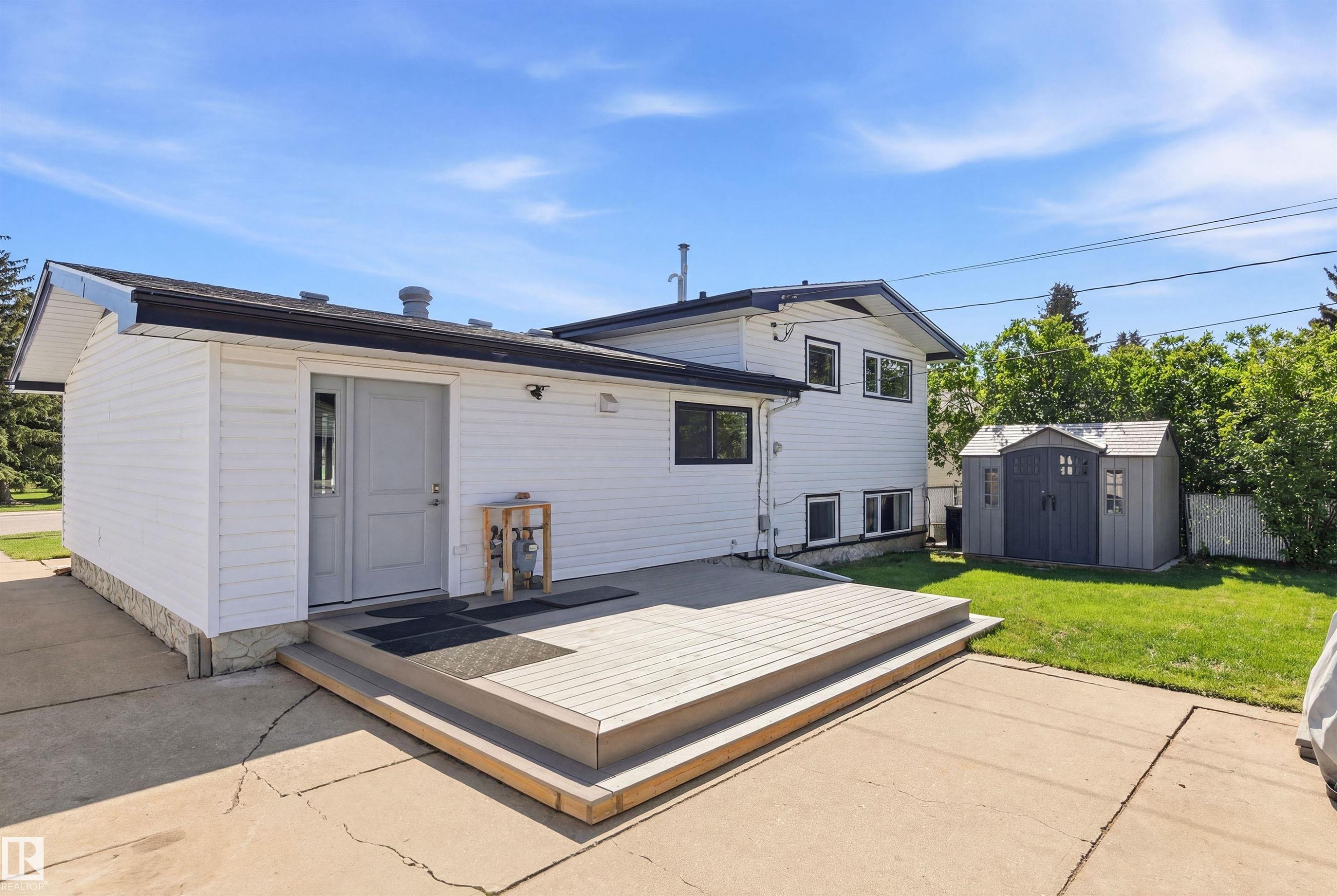 The property features white siding, a wooden deck, and a shed on a green lawn - 12904 95 Street, Edmonton, AB - Outdoor With Exterior