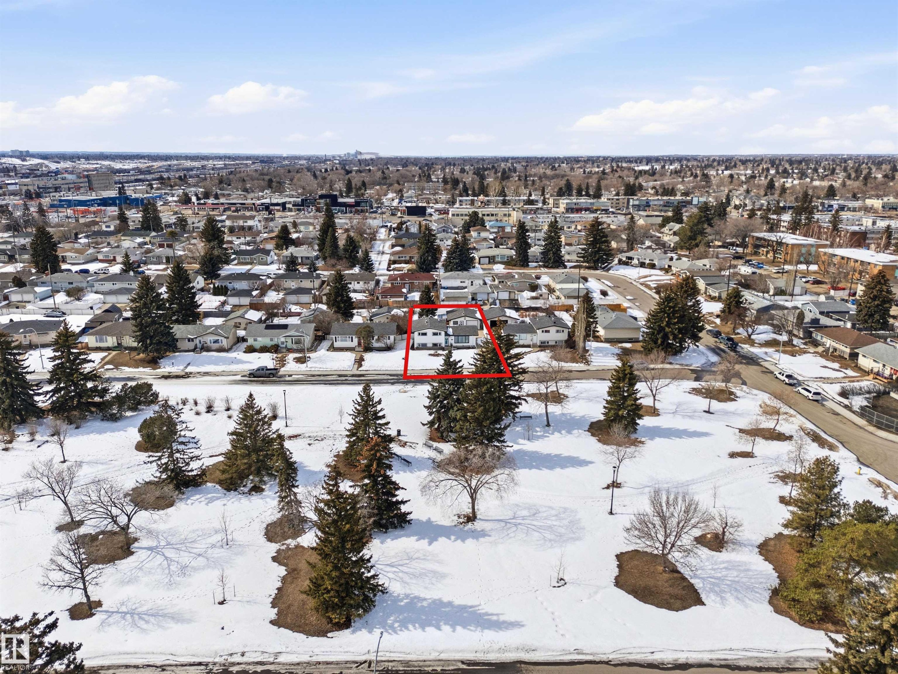 Aerial view of the property and surrounding neighborhood, featuring a residential street and a park area with snow-covered ground and evergreen trees - 12904 95 Street, Edmonton, AB - Outdoor With View