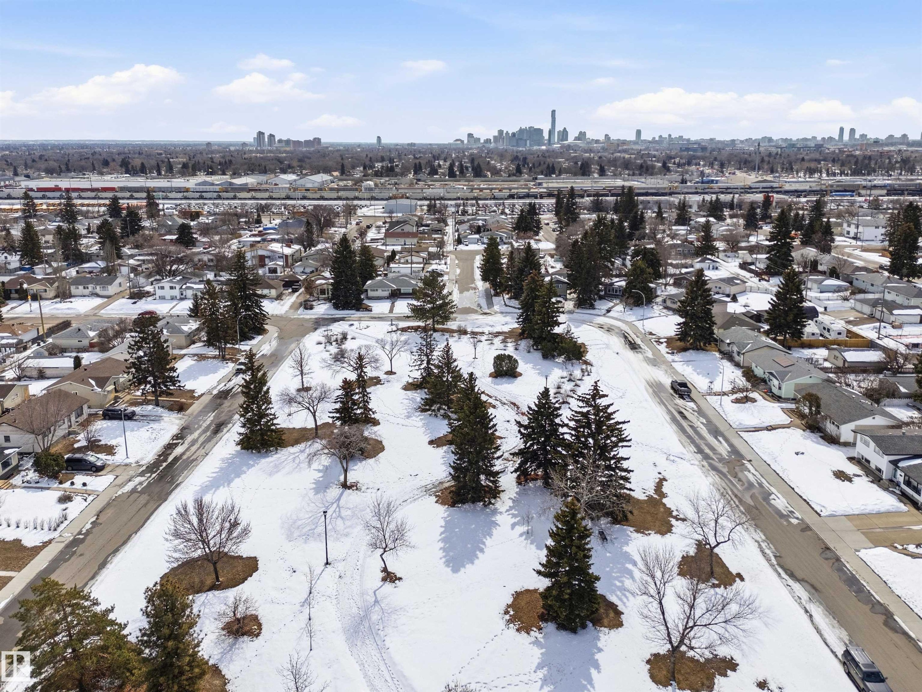 Aerial view showcasing surrounding residential properties with snow-covered grounds and a distant city skyline under a clear sky - 12904 95 Street, Edmonton, AB - Outdoor With View