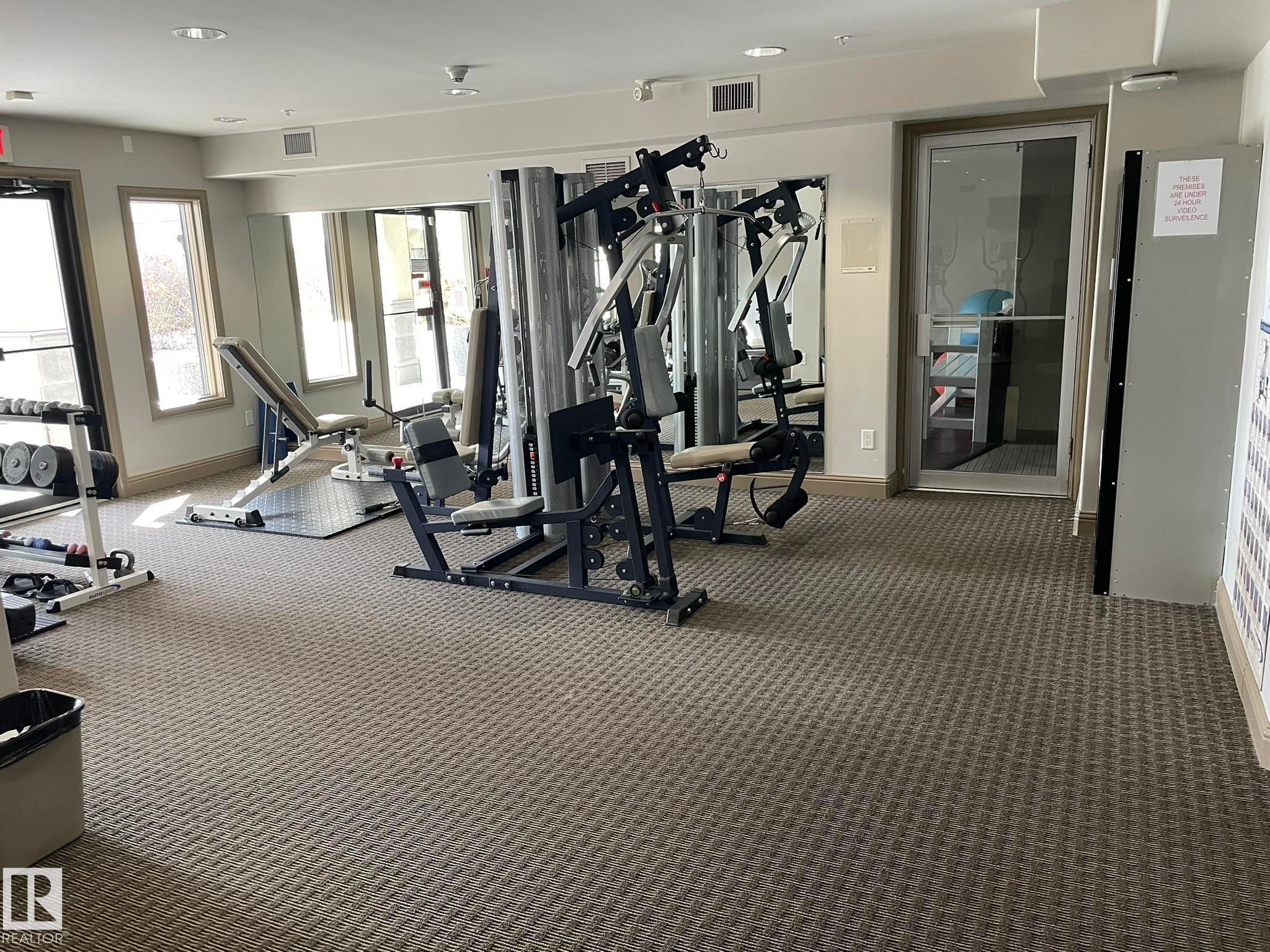 The property features a dedicated fitness area with various exercise machines, including weightlifting equipment and a bench - Edmonton, AB - Indoor Photo Showing Gym Room