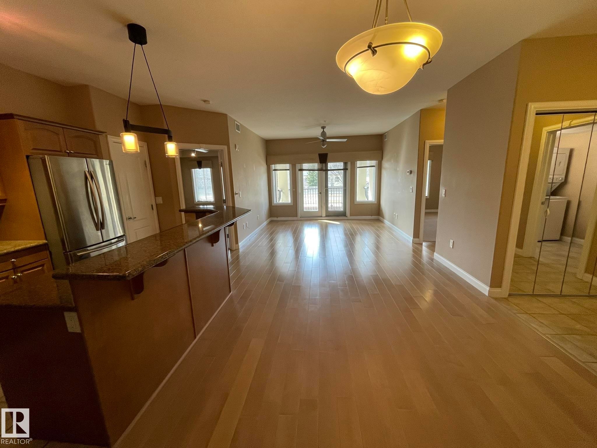 The open concept living area features hardwood flooring, a ceiling fan, and French doors leading to an outdoor space - Edmonton, AB - Indoor