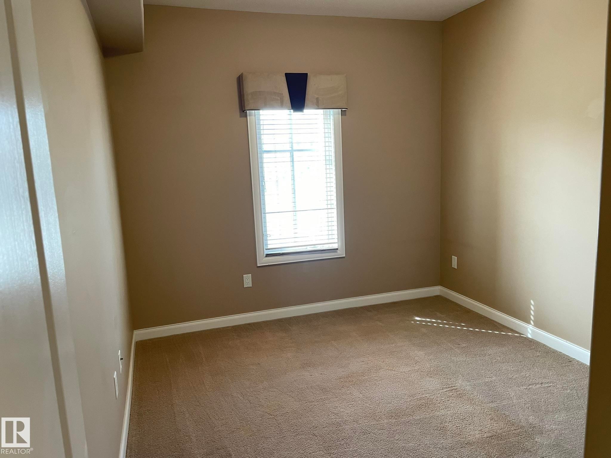 This room features neutral-toned walls, carpeted flooring, and a window with blinds providing natural light - Edmonton, AB - Indoor Photo Showing Other Room