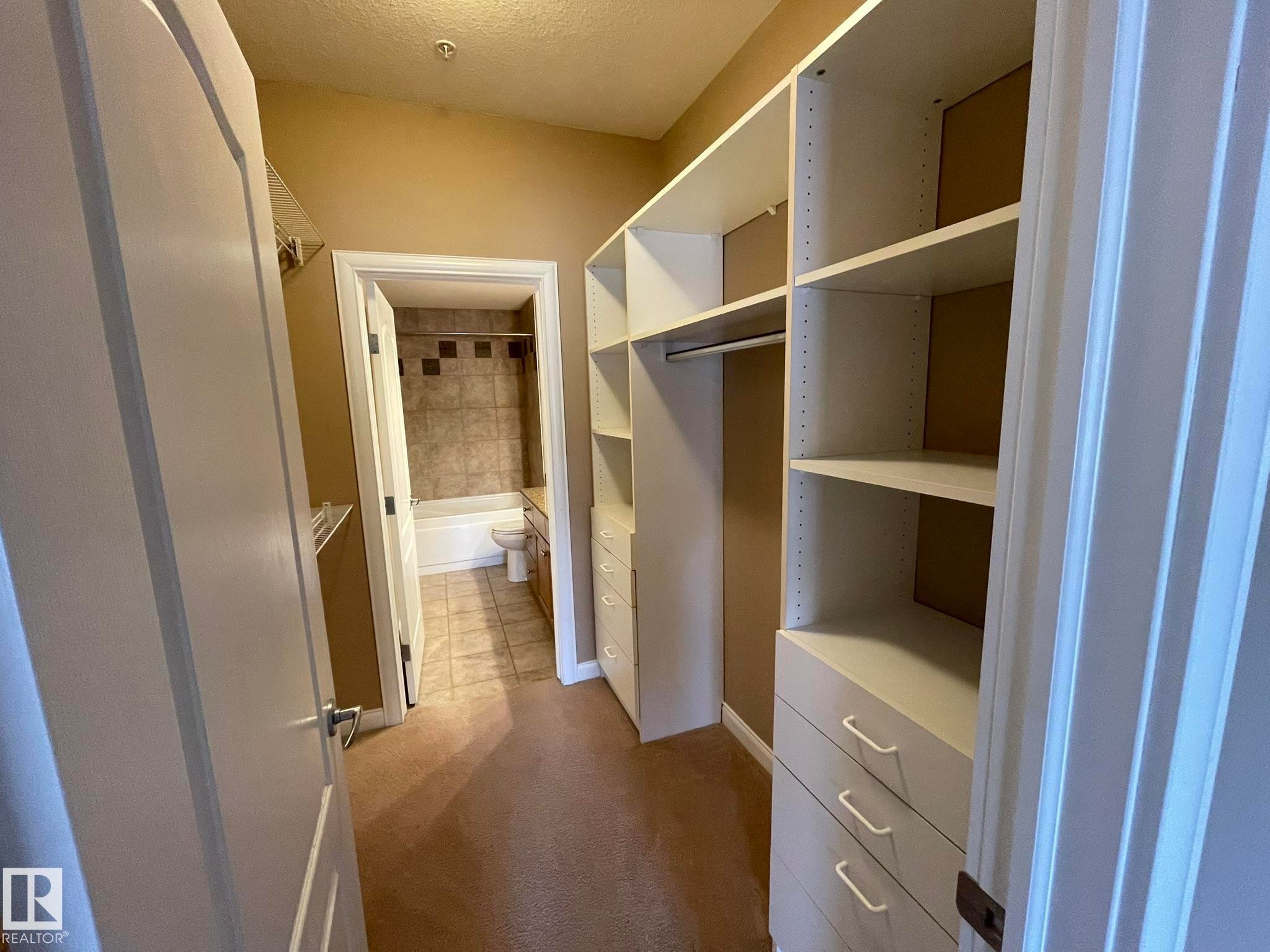 Expansive walk-in closet featuring built-in shelving and drawer units, offering ample storage solutions - Edmonton, AB - Indoor