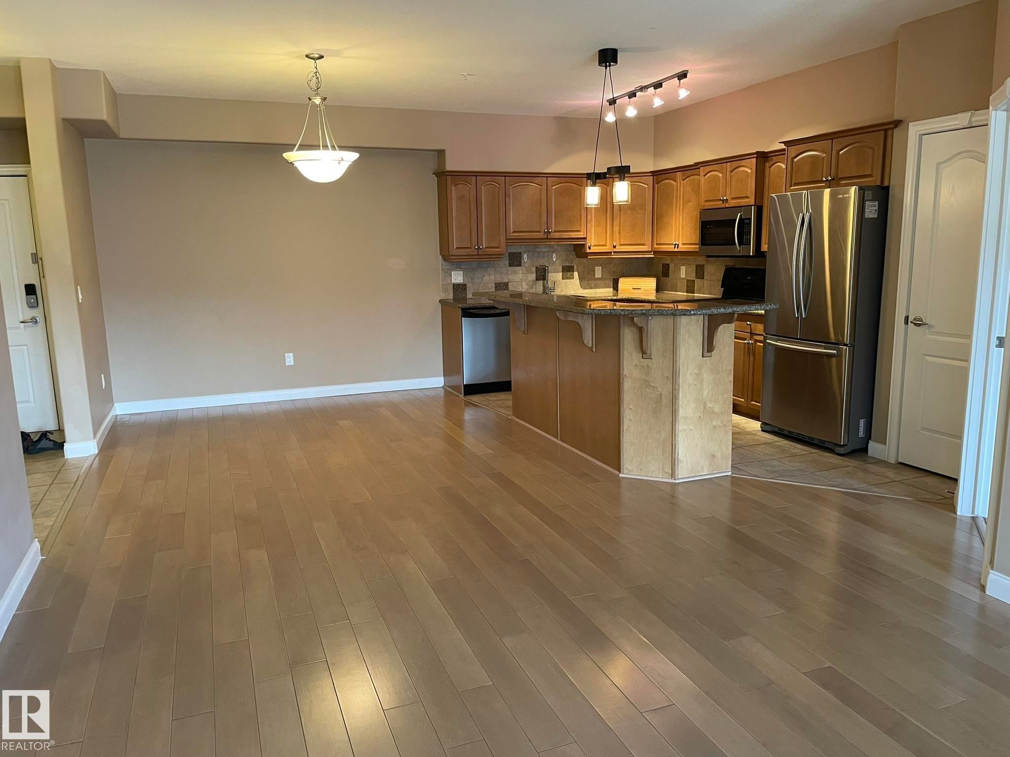 The property features an open concept kitchen and living area with light hardwood flooring - Edmonton, AB - Indoor Photo Showing Kitchen With Stainless Steel Kitchen