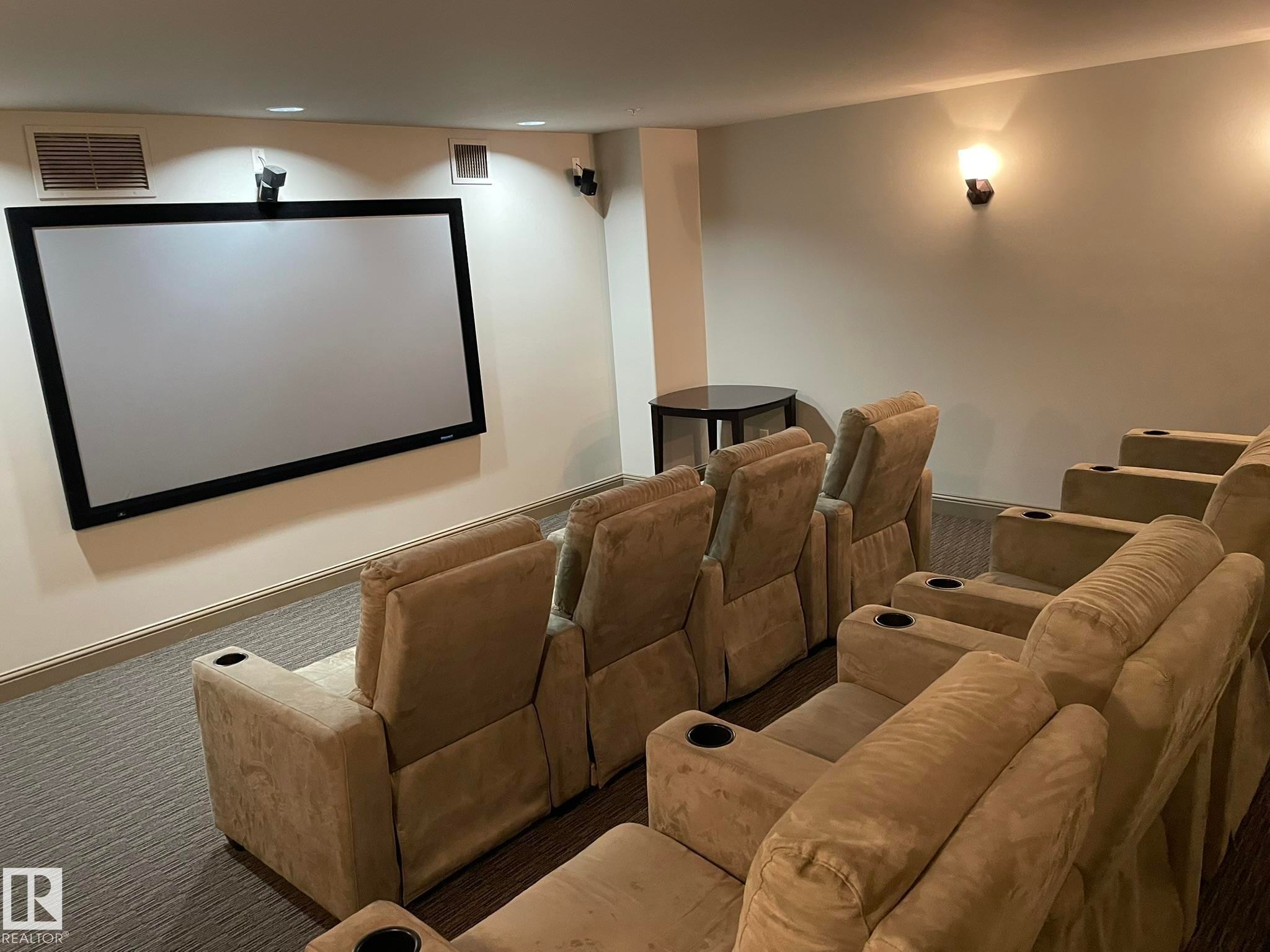 Dedicated media room featuring a large projection screen, wall-mounted speakers, and comfortable tiered seating - Edmonton, AB - Indoor Photo Showing Other Room