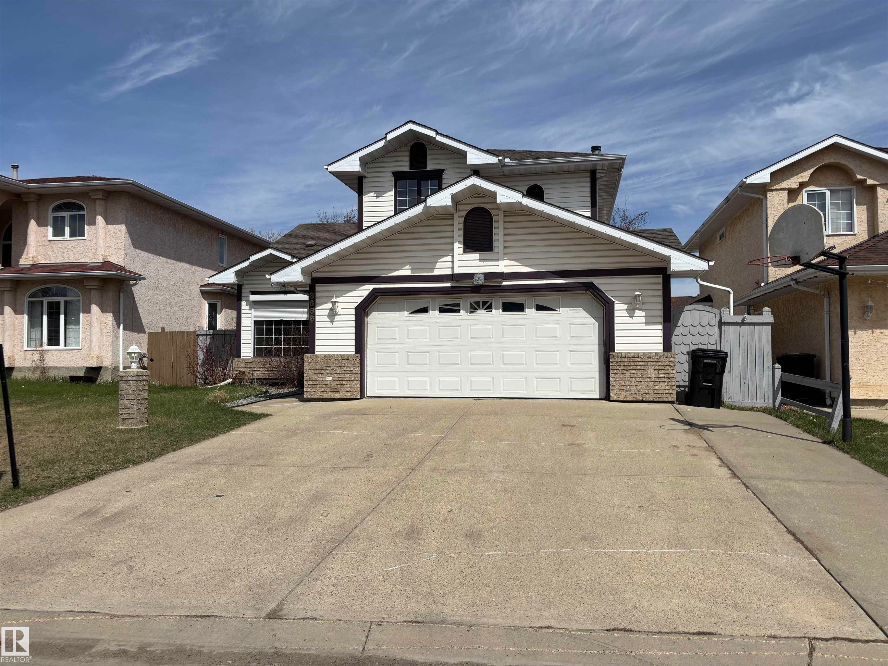 Two-story residence featuring a prominent front-facing garage with a white door, a concrete driveway, and a white siding exterior - 3668 31A Street, Edmonton, AB - Outdoor