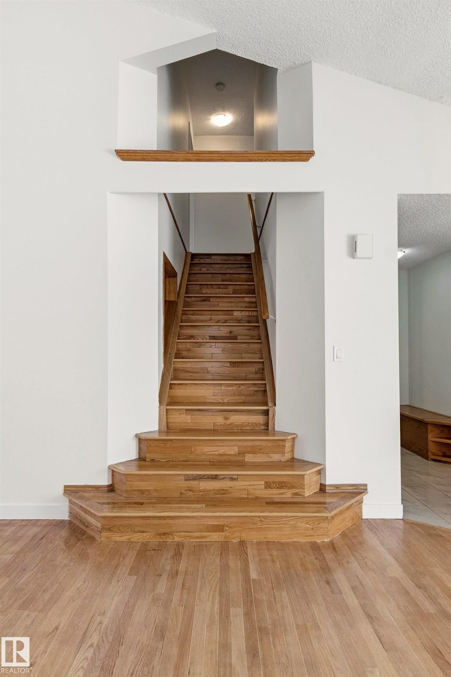 The property features hardwood floors and a wooden staircase with a matching banister - 3668 31A Street, Edmonton, AB - Indoor Photo Showing Other Room