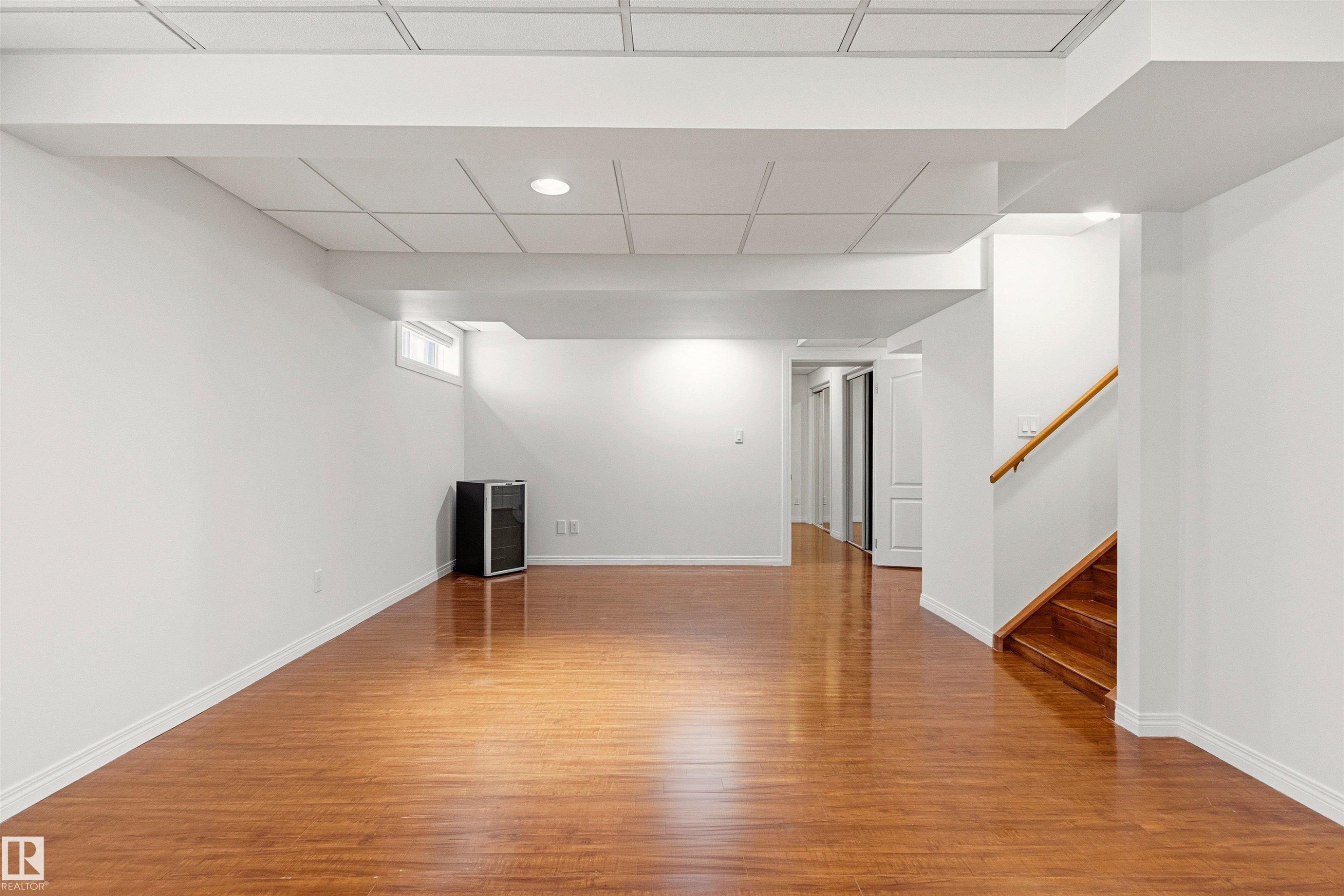 Expansive room featuring hardwood floors, white walls, and recessed lighting, with a wooden staircase and hallway visible - 3668 31A Street, Edmonton, AB - Indoor Photo Showing Other Room