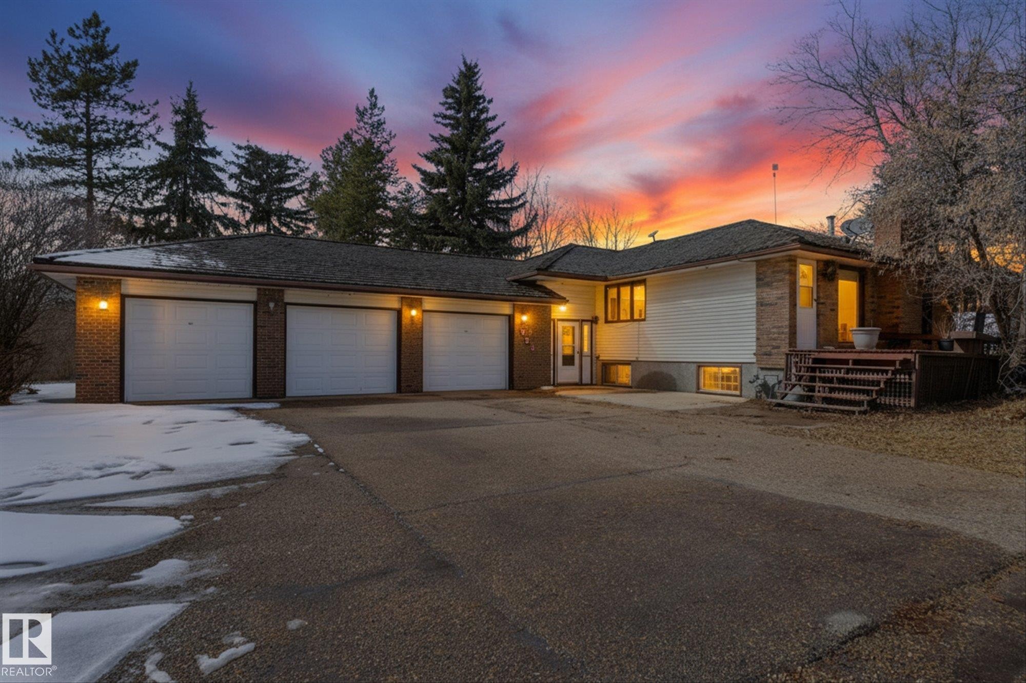 Residence exterior featuring a three-car garage, brick accents, and a multi-level deck - 25750 18 Street, Edmonton, AB - Outdoor