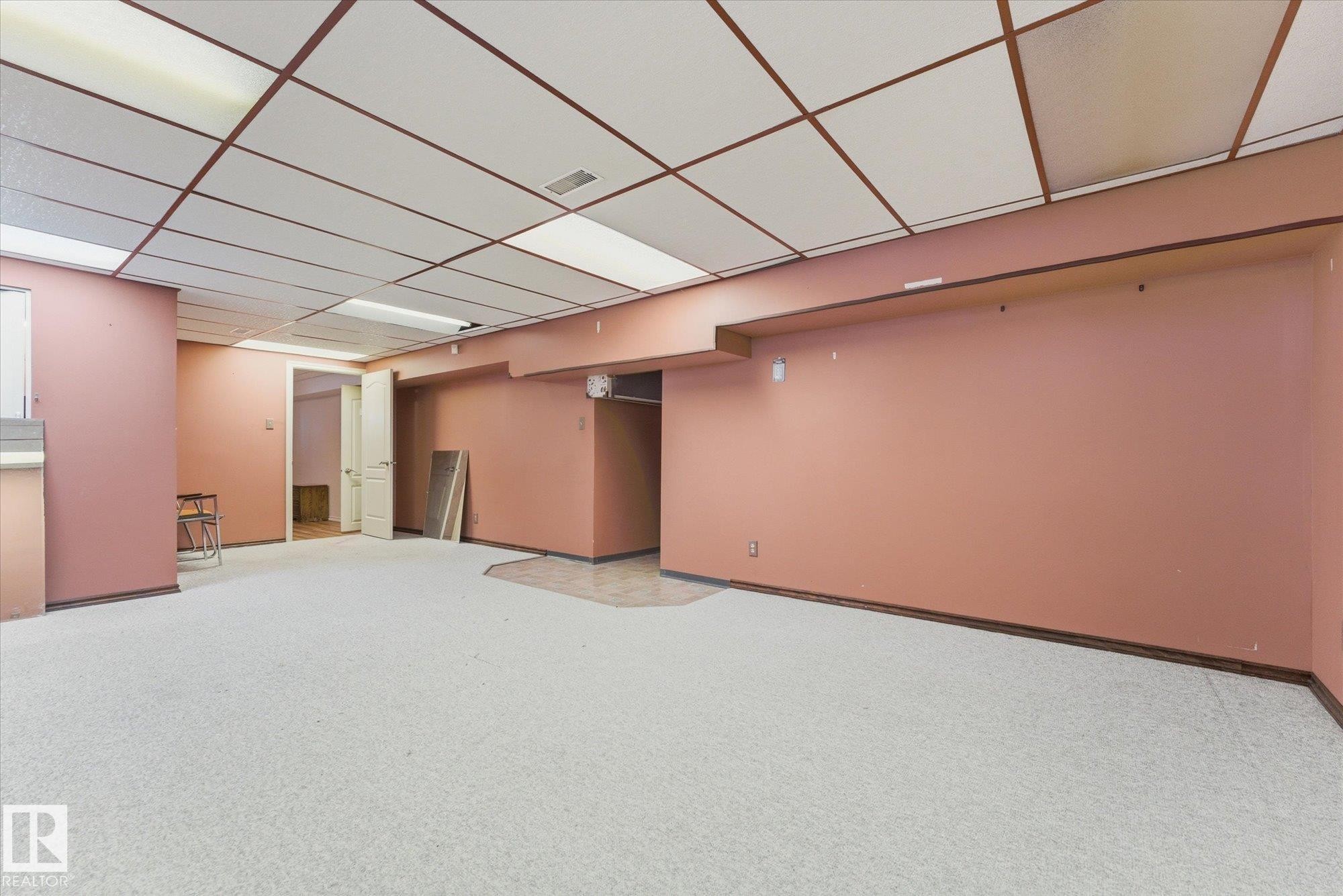 Spacious interior room with light-colored carpet flooring and a suspended ceiling with integrated lighting panels - 25750 18 Street, Edmonton, AB - Indoor