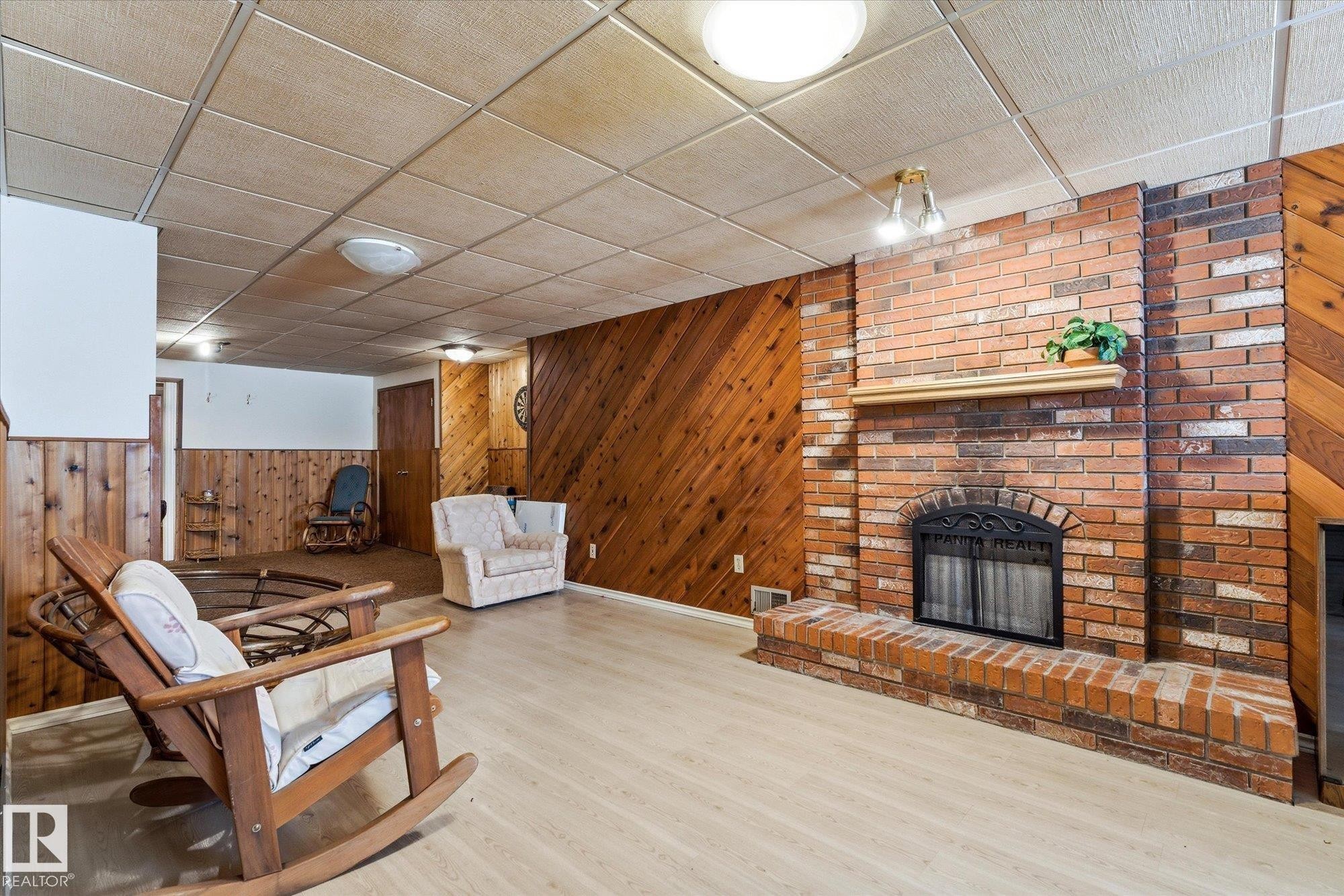 Brick fireplace with a wood mantle, complemented by wood paneling and wood-finish flooring - 25750 18 Street, Edmonton, AB - Indoor With Fireplace