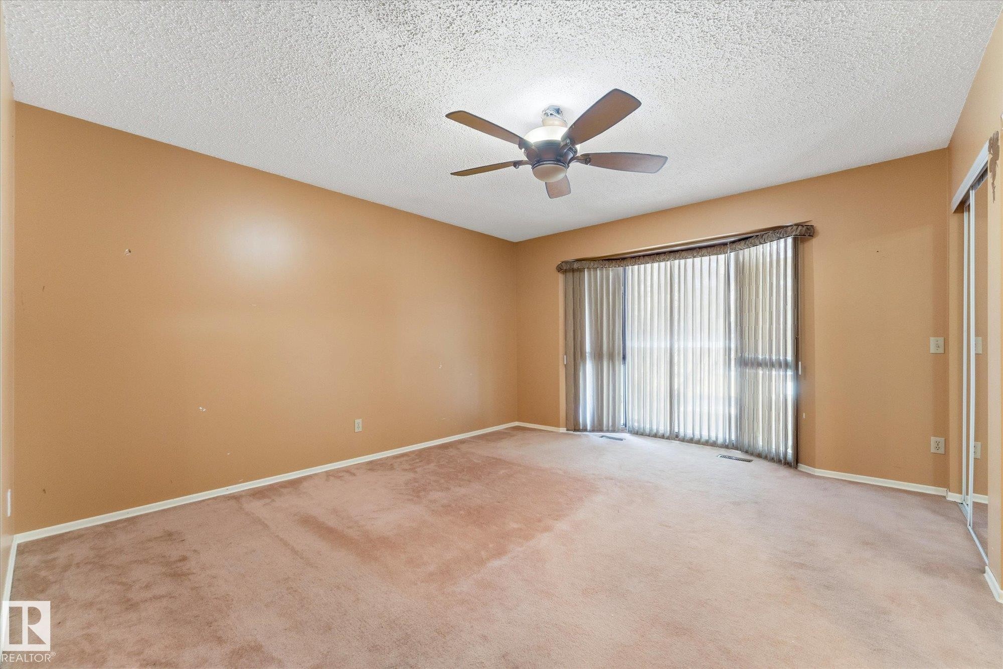 Room featuring carpet flooring, painted walls, a textured ceiling, a ceiling fan with light fixture, and a large window with vertical blinds - 25750 18 Street, Edmonton, AB - Indoor Photo Showing Other Room